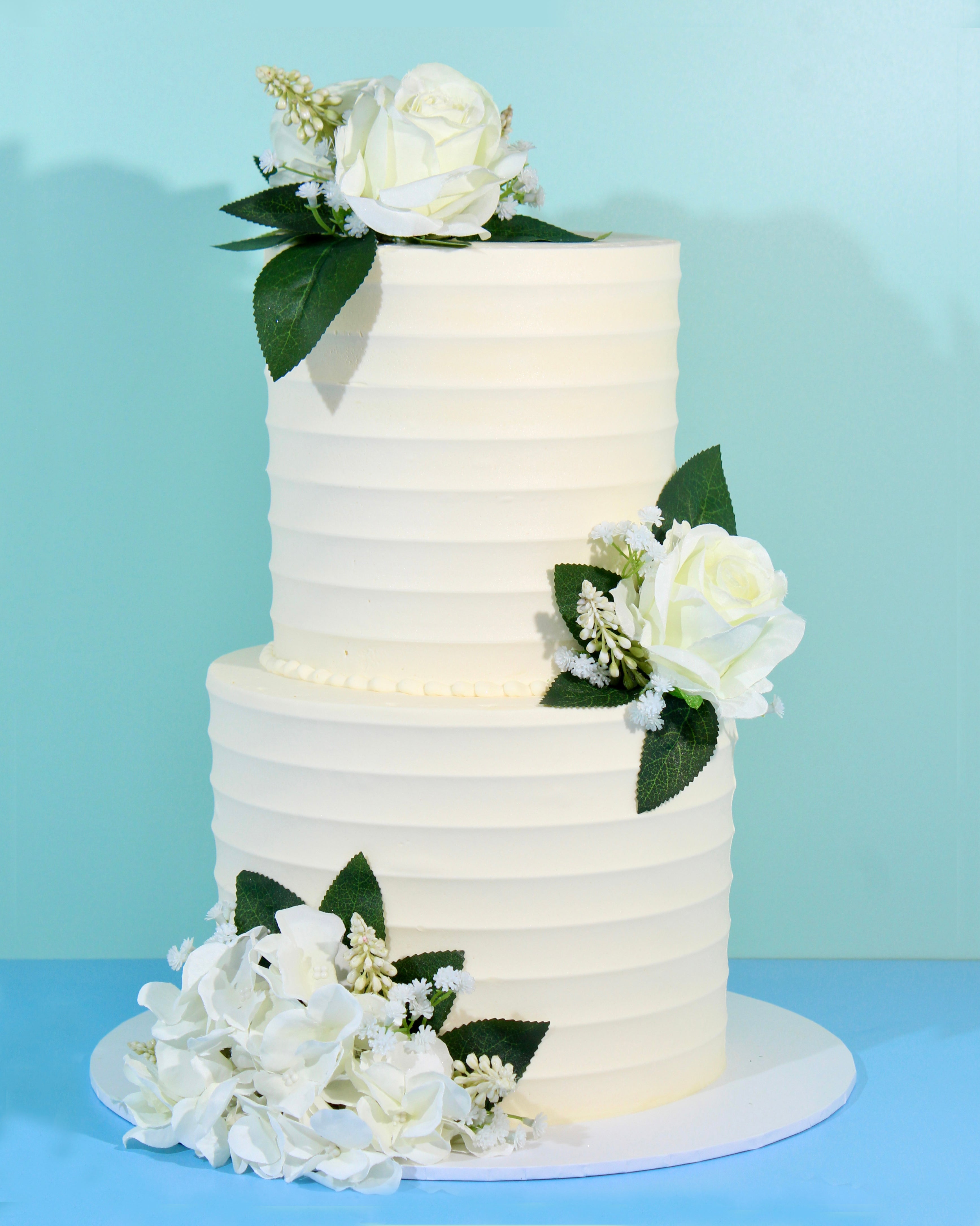 Classic two-tier white wedding cake with subtle textured icing and floral accents