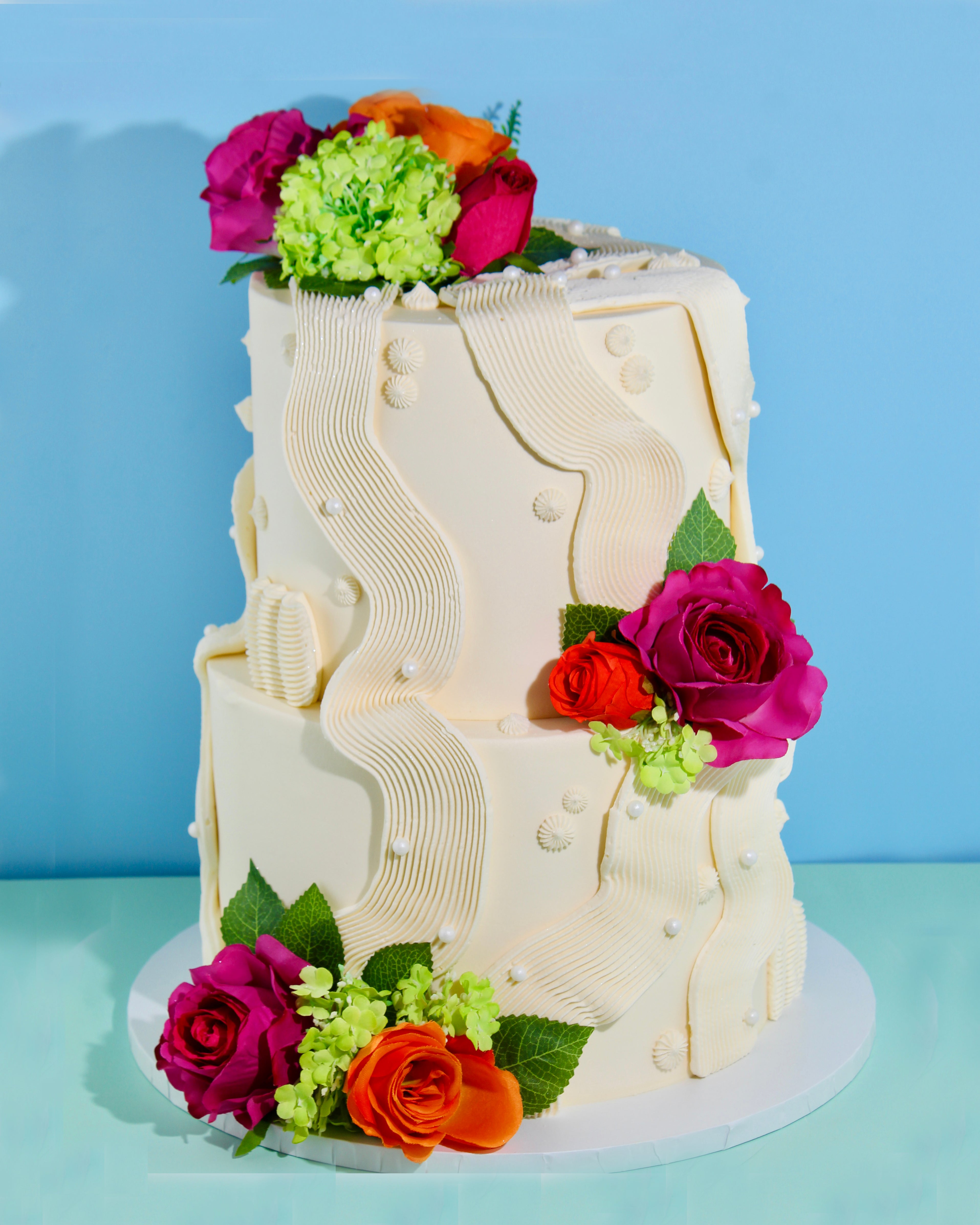 Modern wedding cake with sculpted ripple icing and colourful floral accents