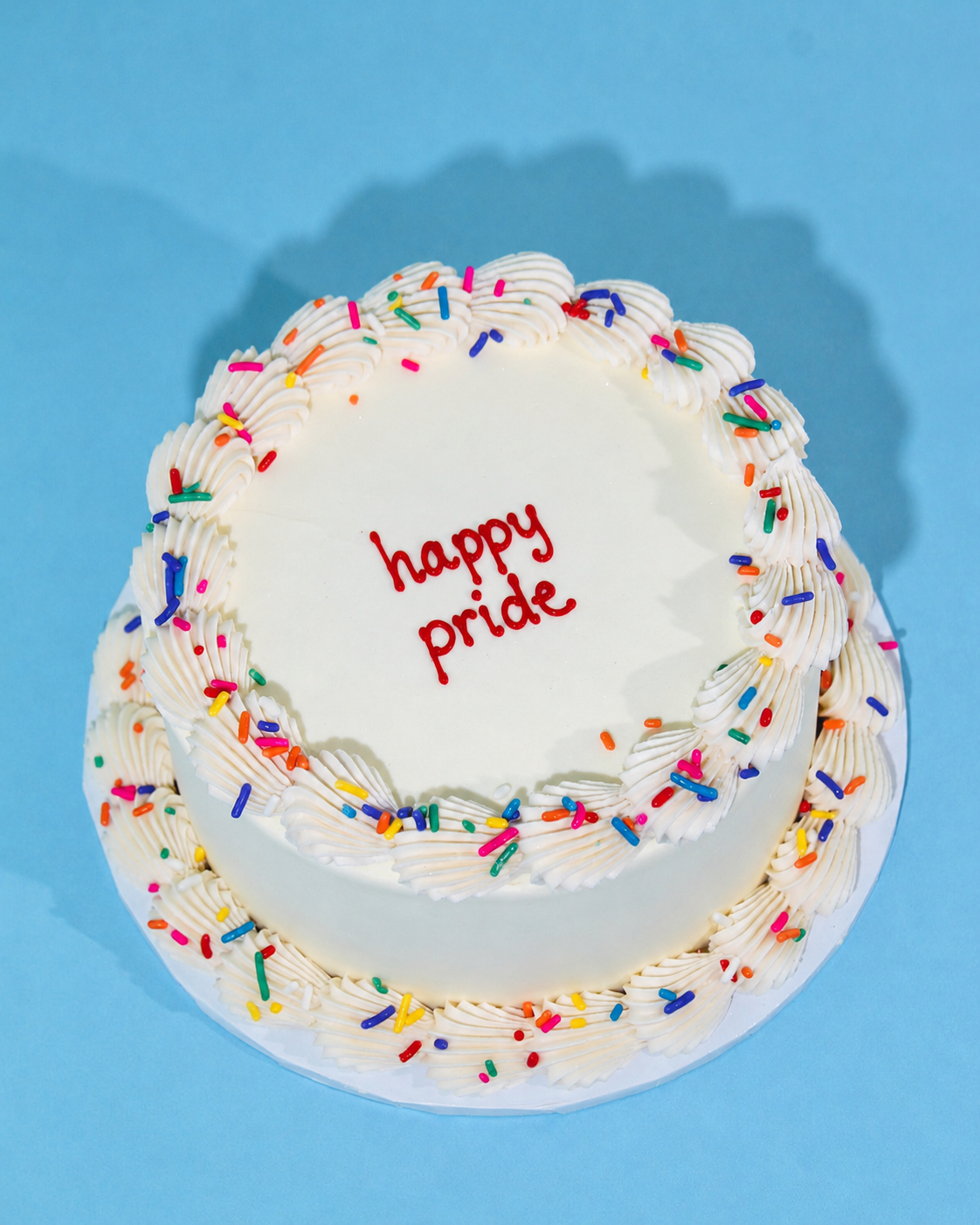 Mini Pride Cake finished in smooth white buttercream with piped borders and colourful rainbow sprinkles, perfect for Pride celebrations, birthdays and small gatherings.