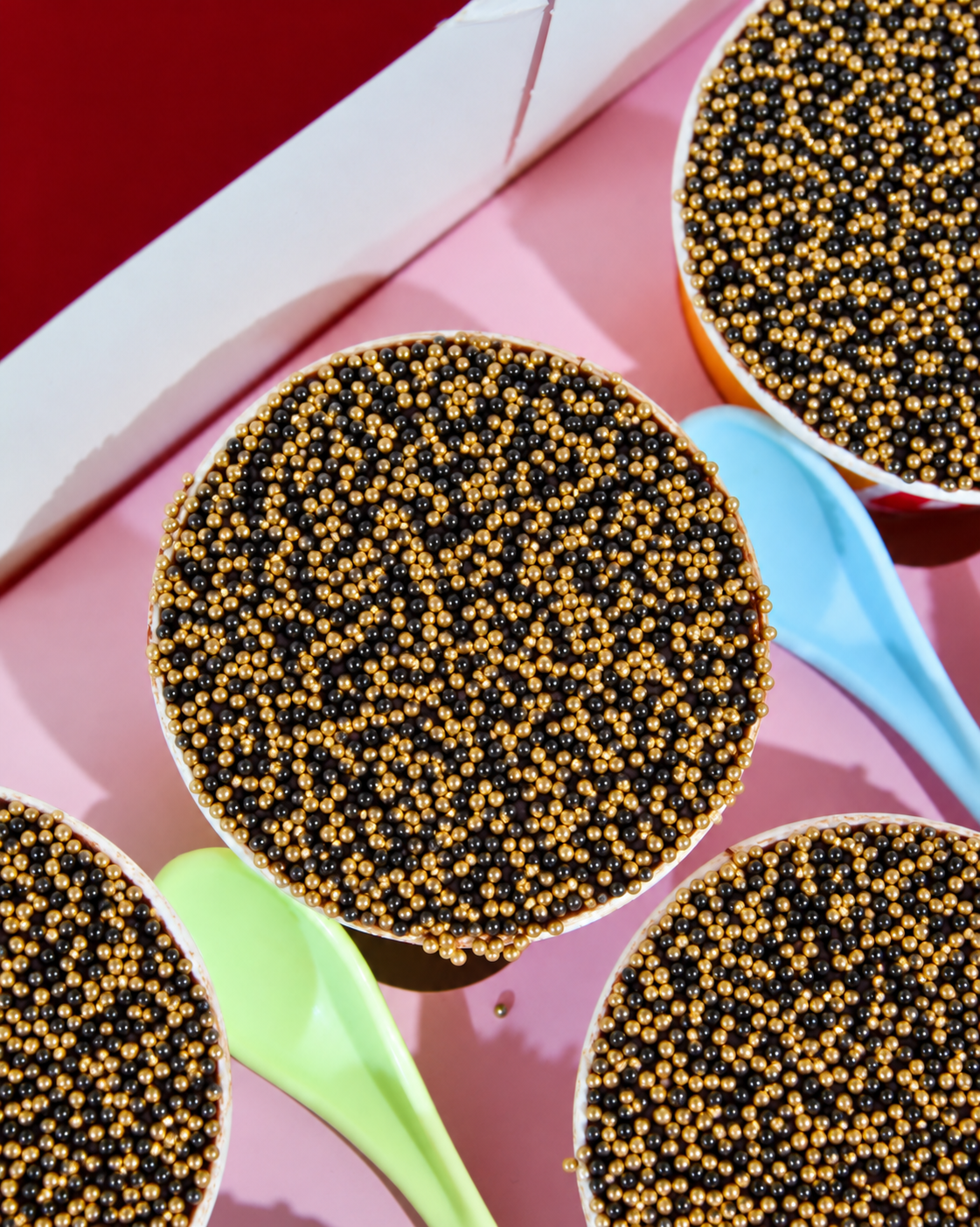 Close-up of black and gold sprinkle Bonfire Night Dot Cake in Amy's Bakehouse branded cup with colourful spoon