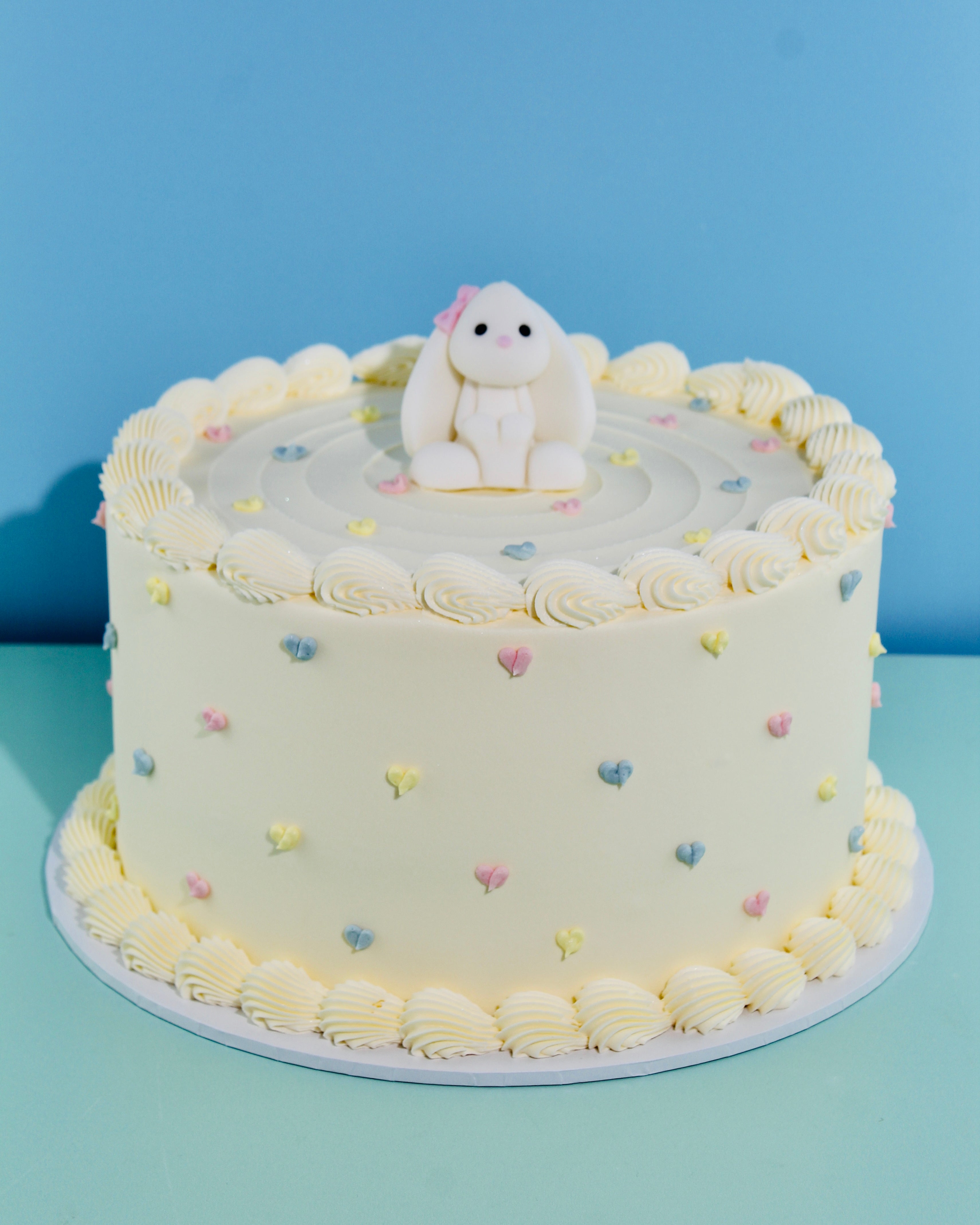 Cute white bunny birthday cake with pastel heart piping and smooth buttercream finish