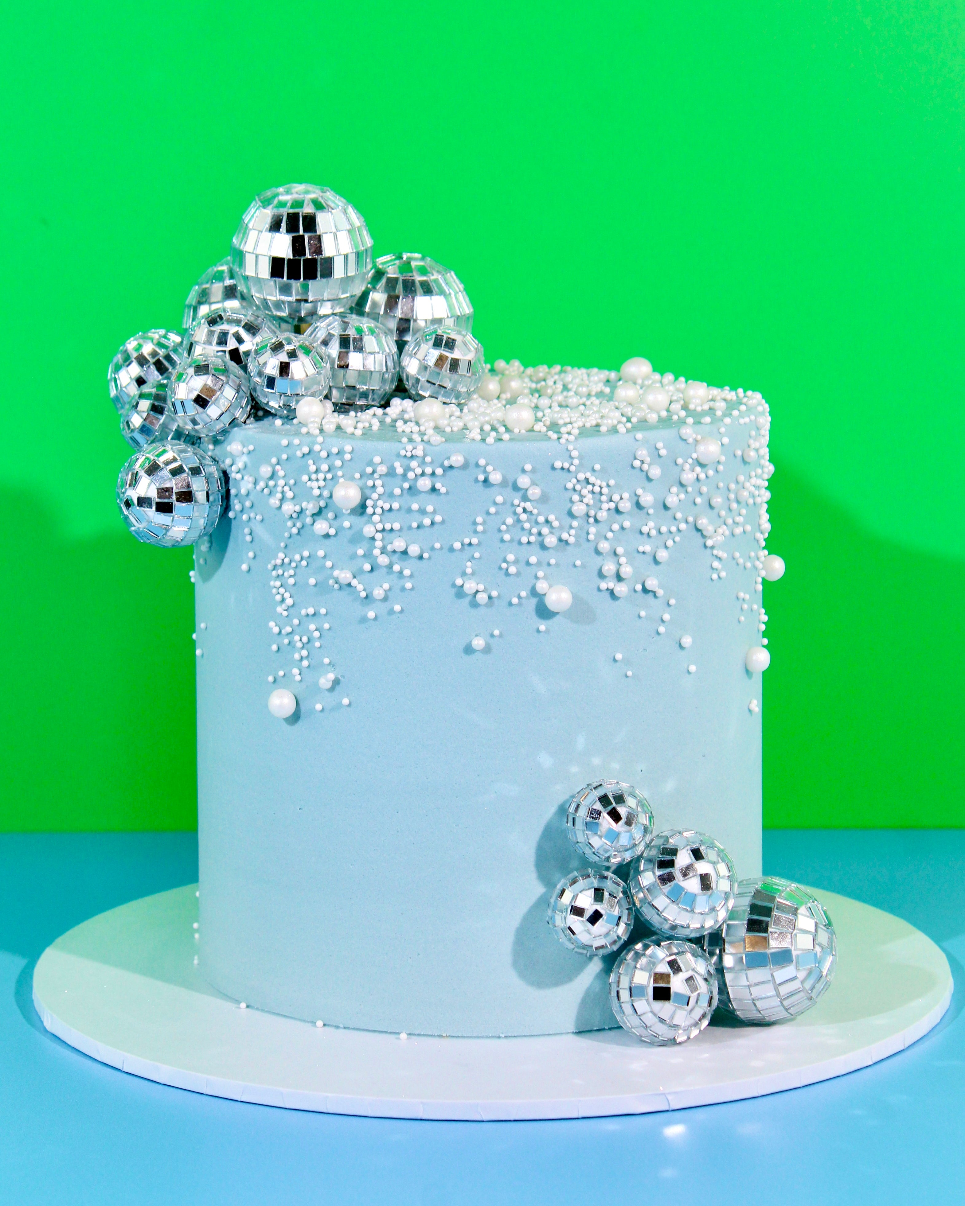 Pastel blue cake decorated with silver disco balls and white sugar pearls