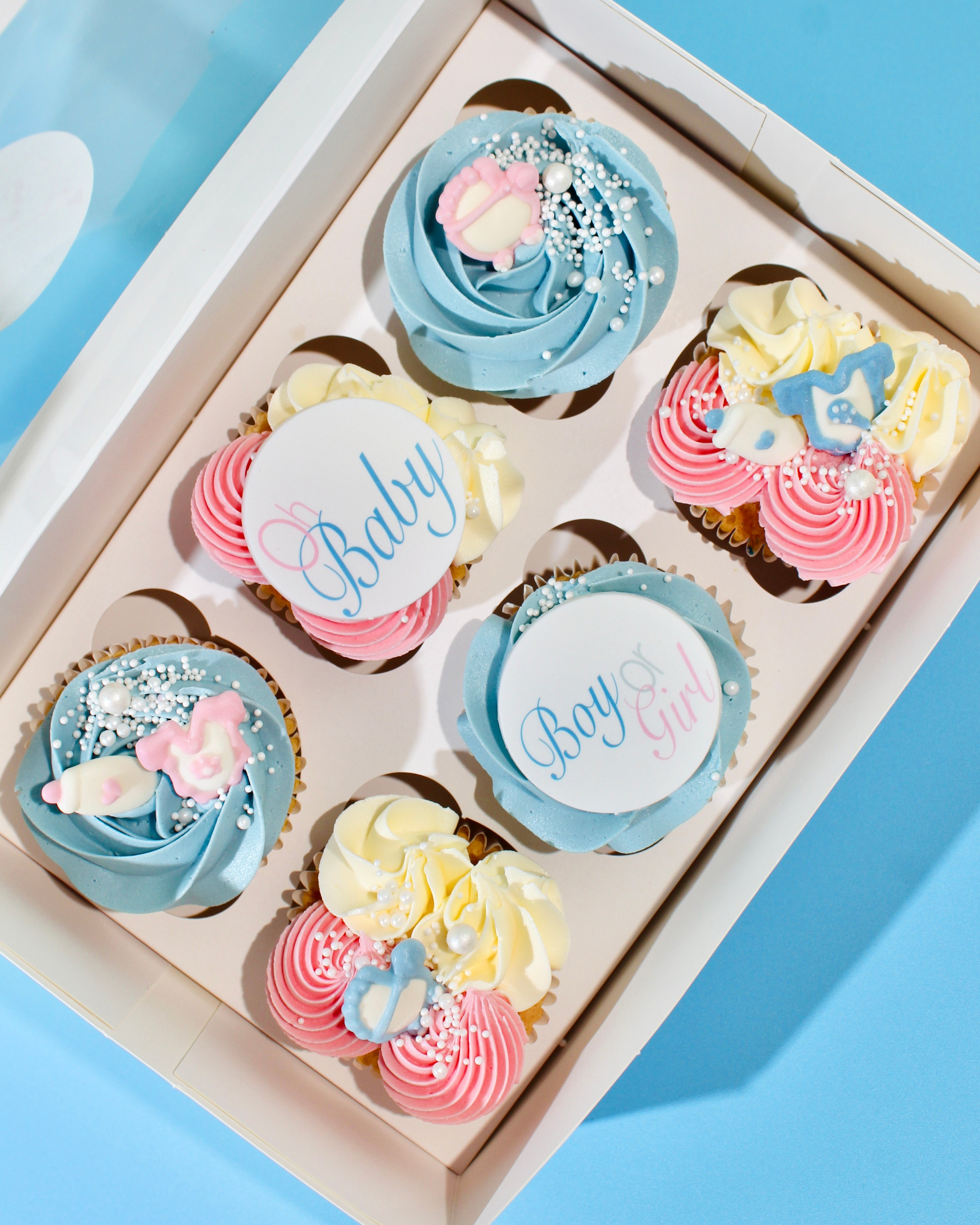 Gender Reveal Cupcakes decorated with pink and blue buttercream and baby-themed toppers.