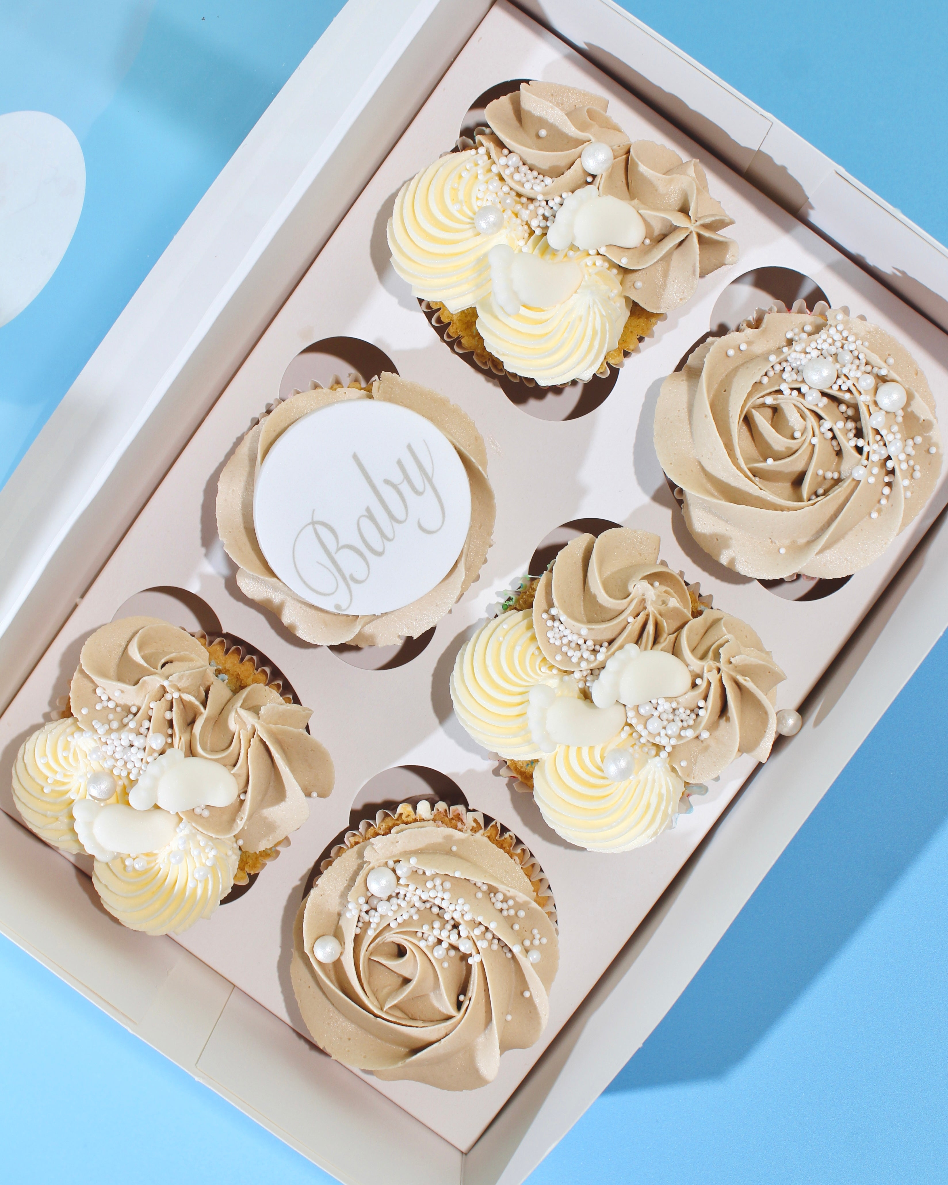 Baby shower cupcakes with beige and cream buttercream and baby toppers