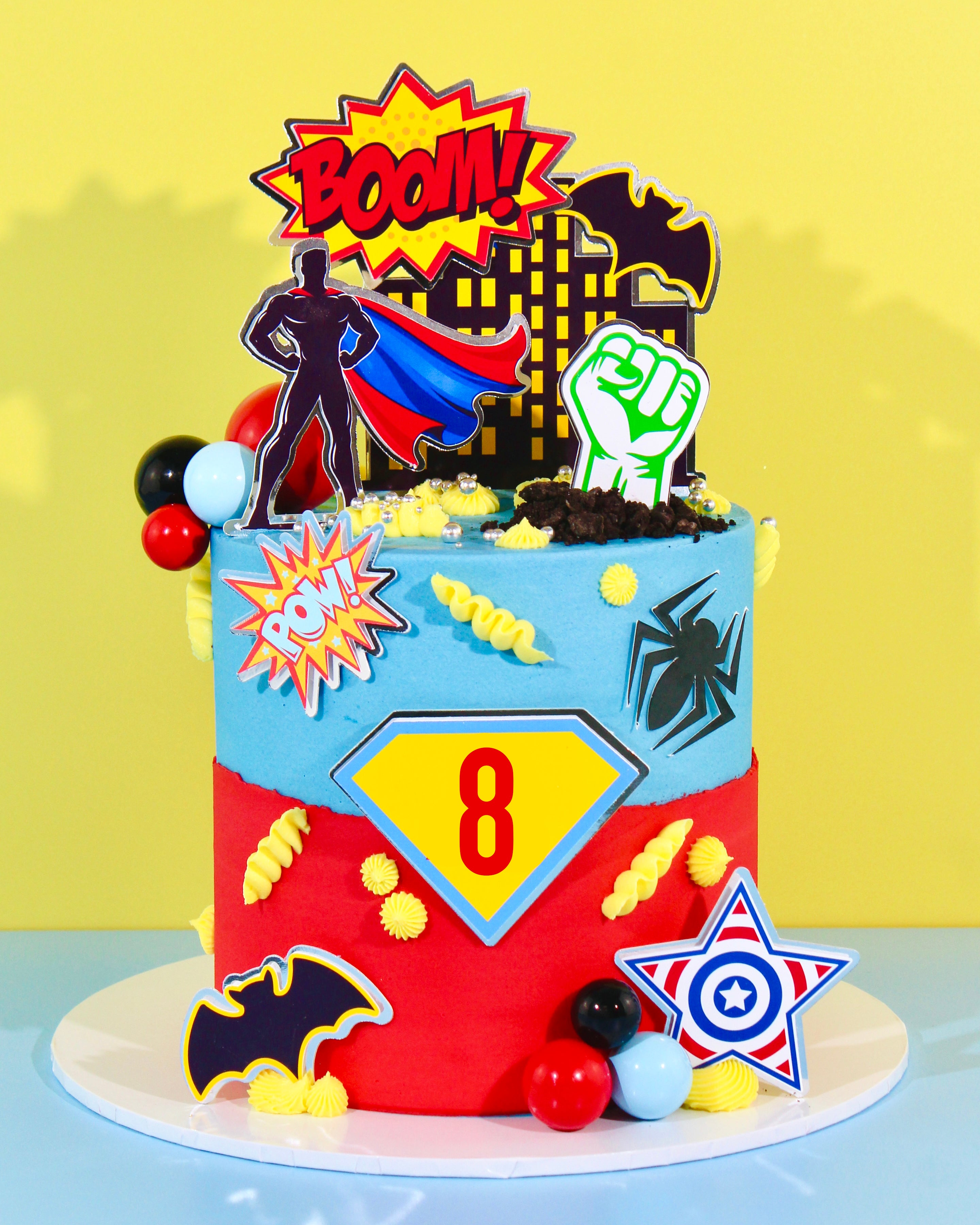 Custom superhero birthday cake with comic-style toppers and colourful decorations.