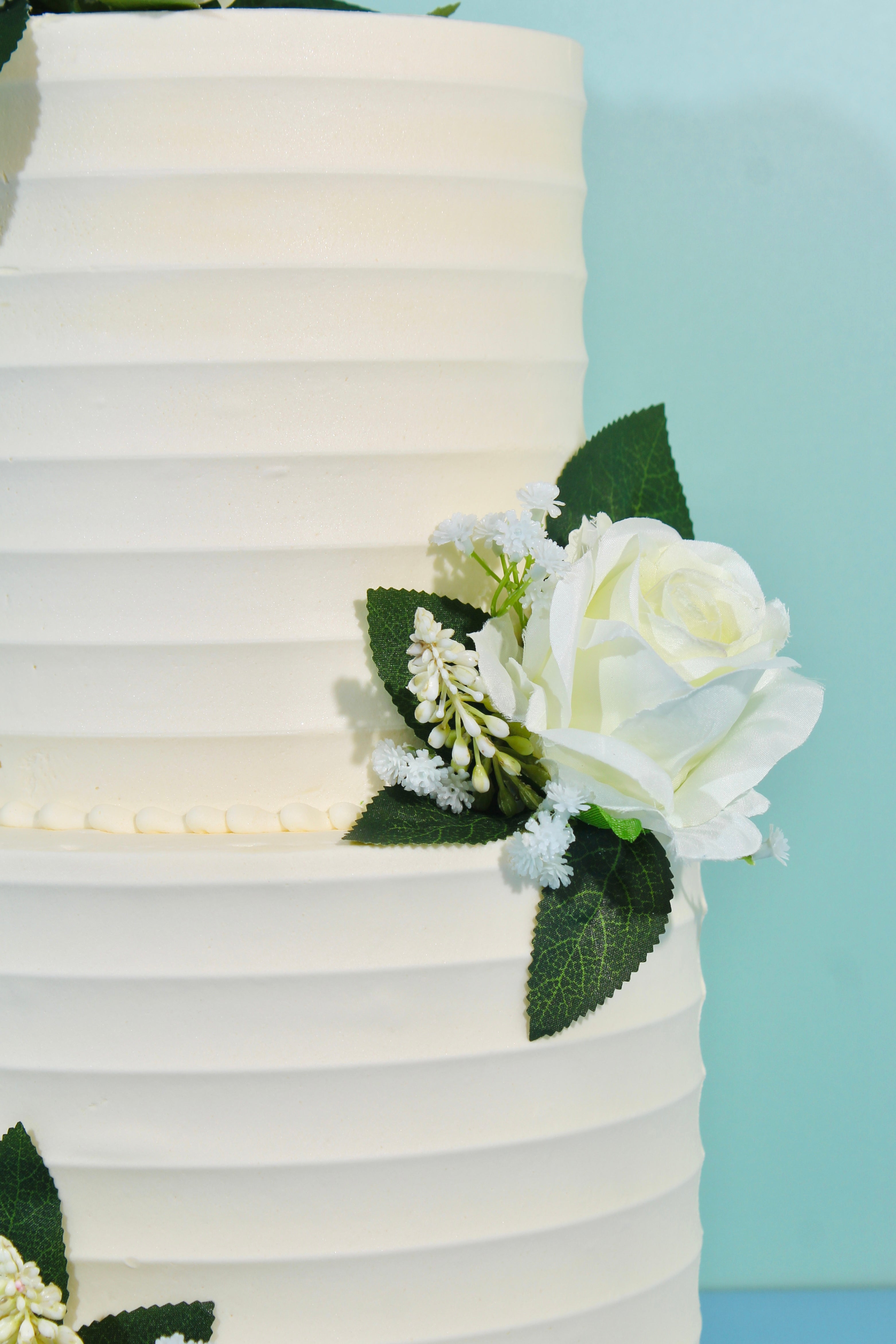 Classic two-tier white wedding cake with subtle textured icing and floral accents