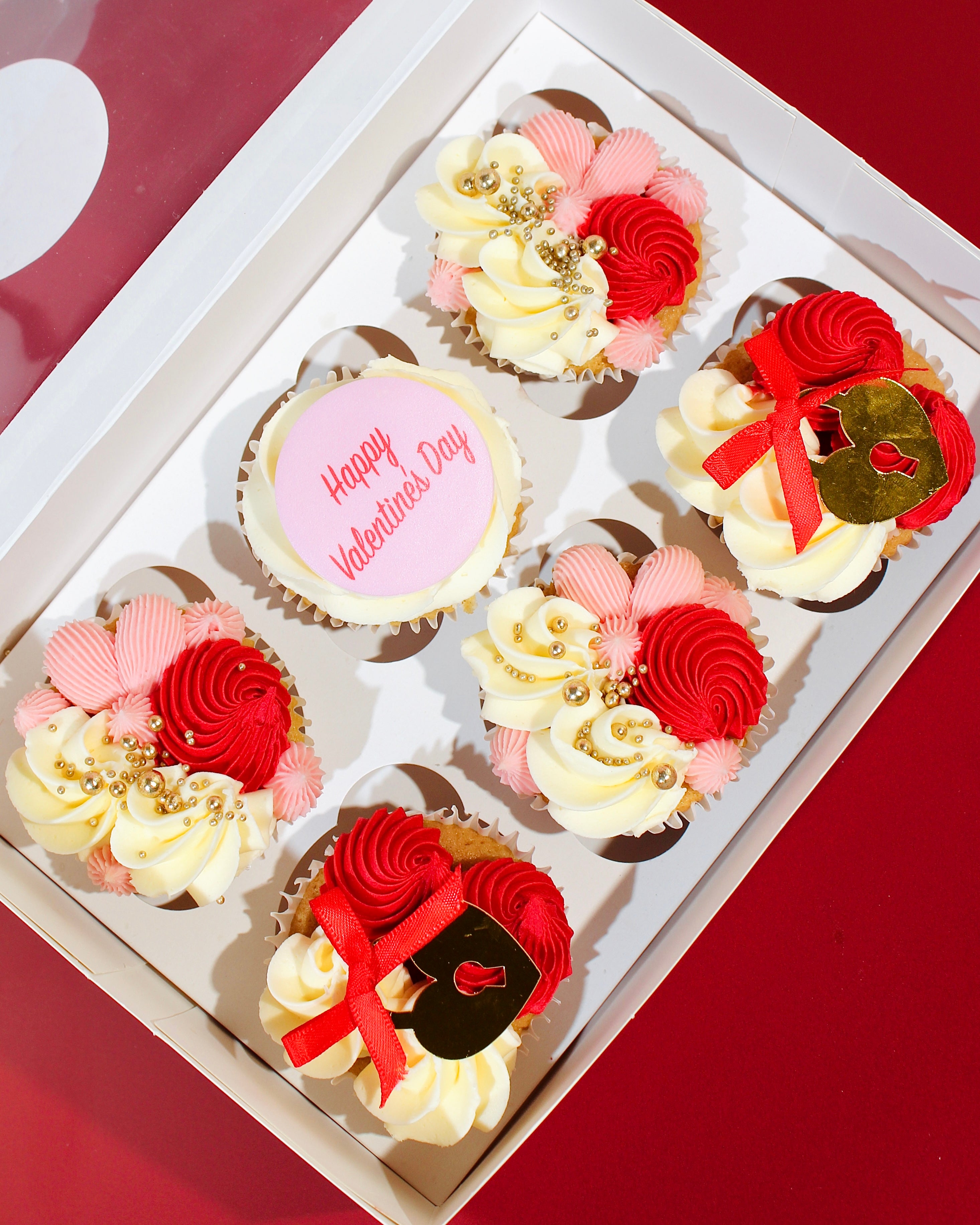 Box of Valentine’s heart locket cupcakes decorated with red, pink and vanilla buttercream