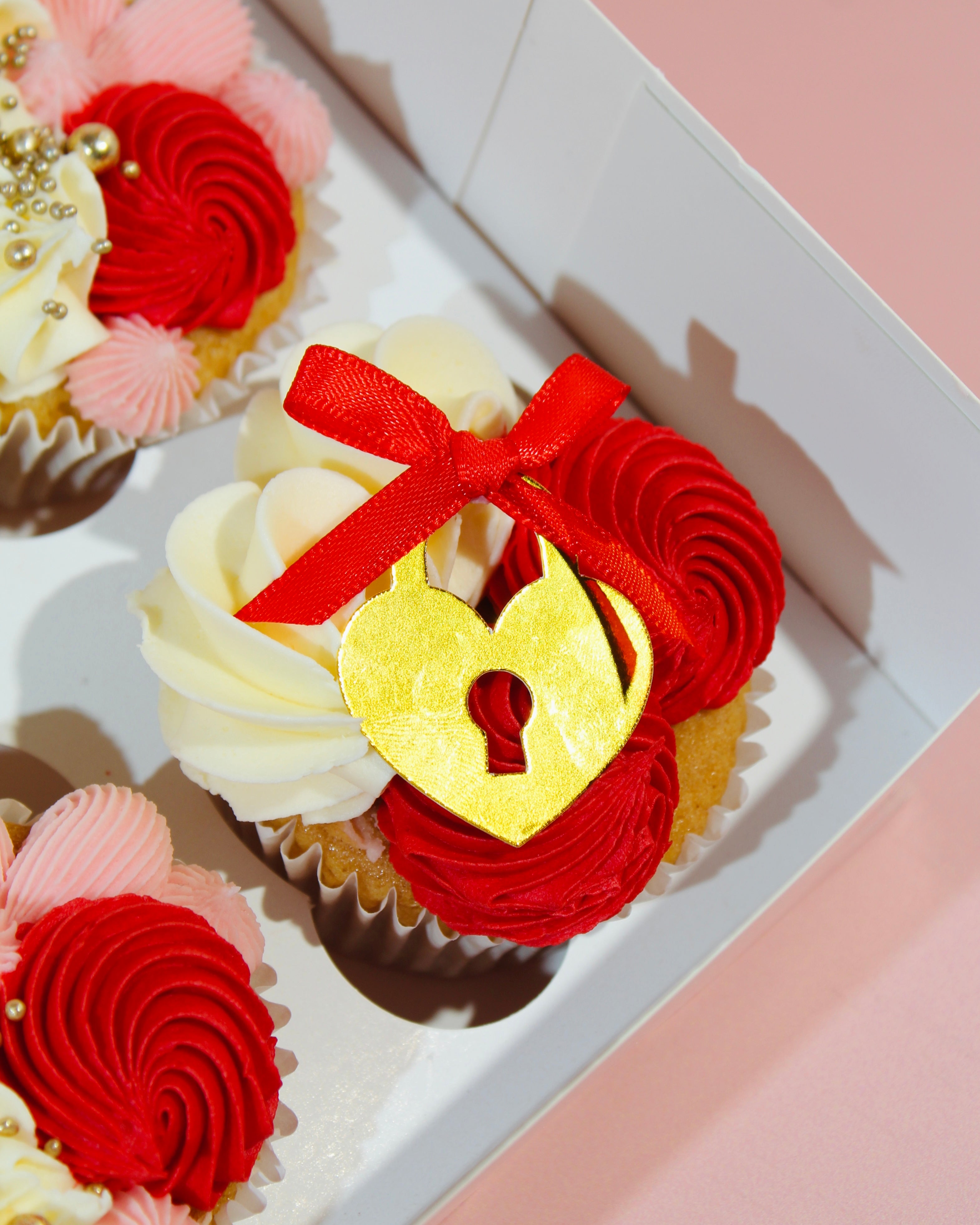 Close-up of cupcake with gold heart locket topper and red ribbon bow