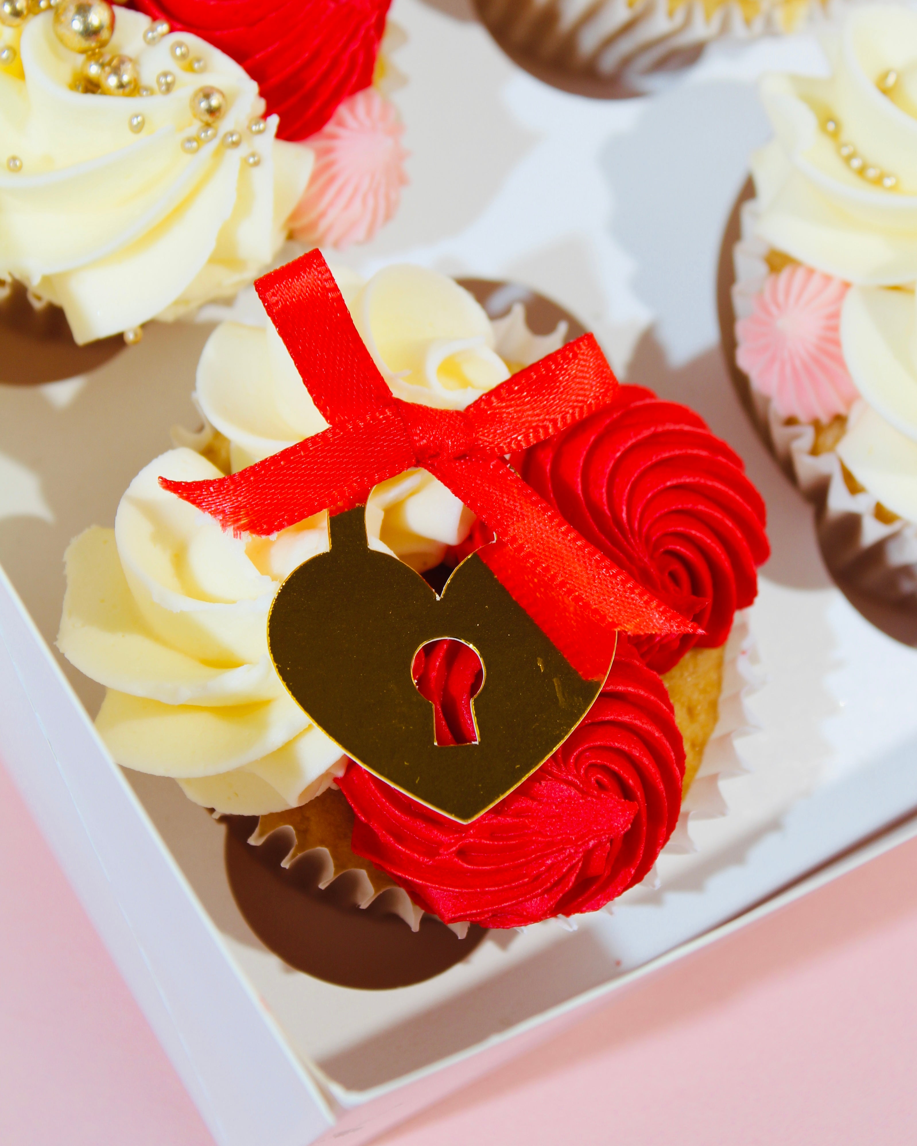 Valentine’s cupcakes with red and blush buttercream swirls and gold locket decoration