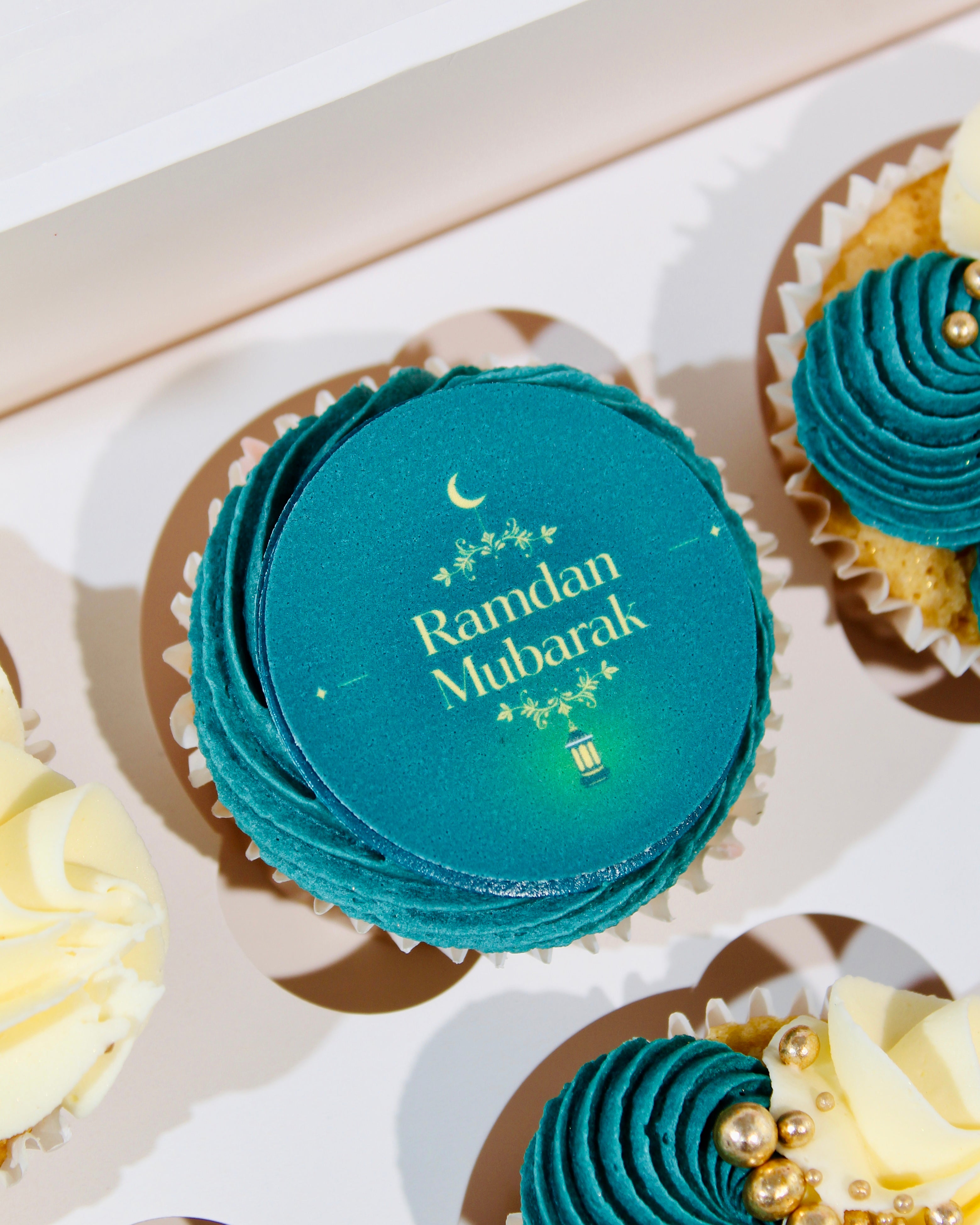Close-up of Ramadan cupcake with teal icing and gold decorative pearls