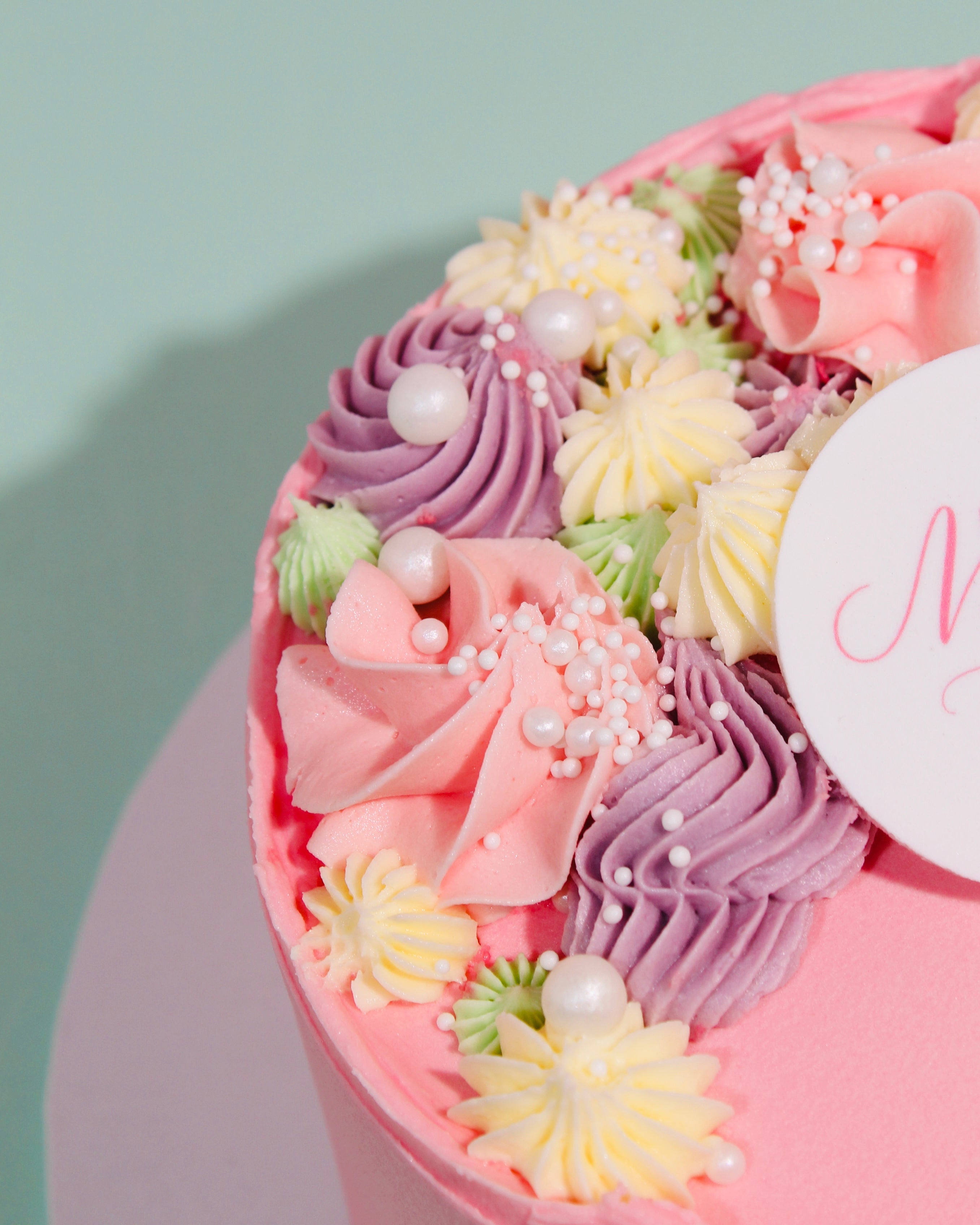 Decorative cake with pink, purple, and yellow frosting on a light green background