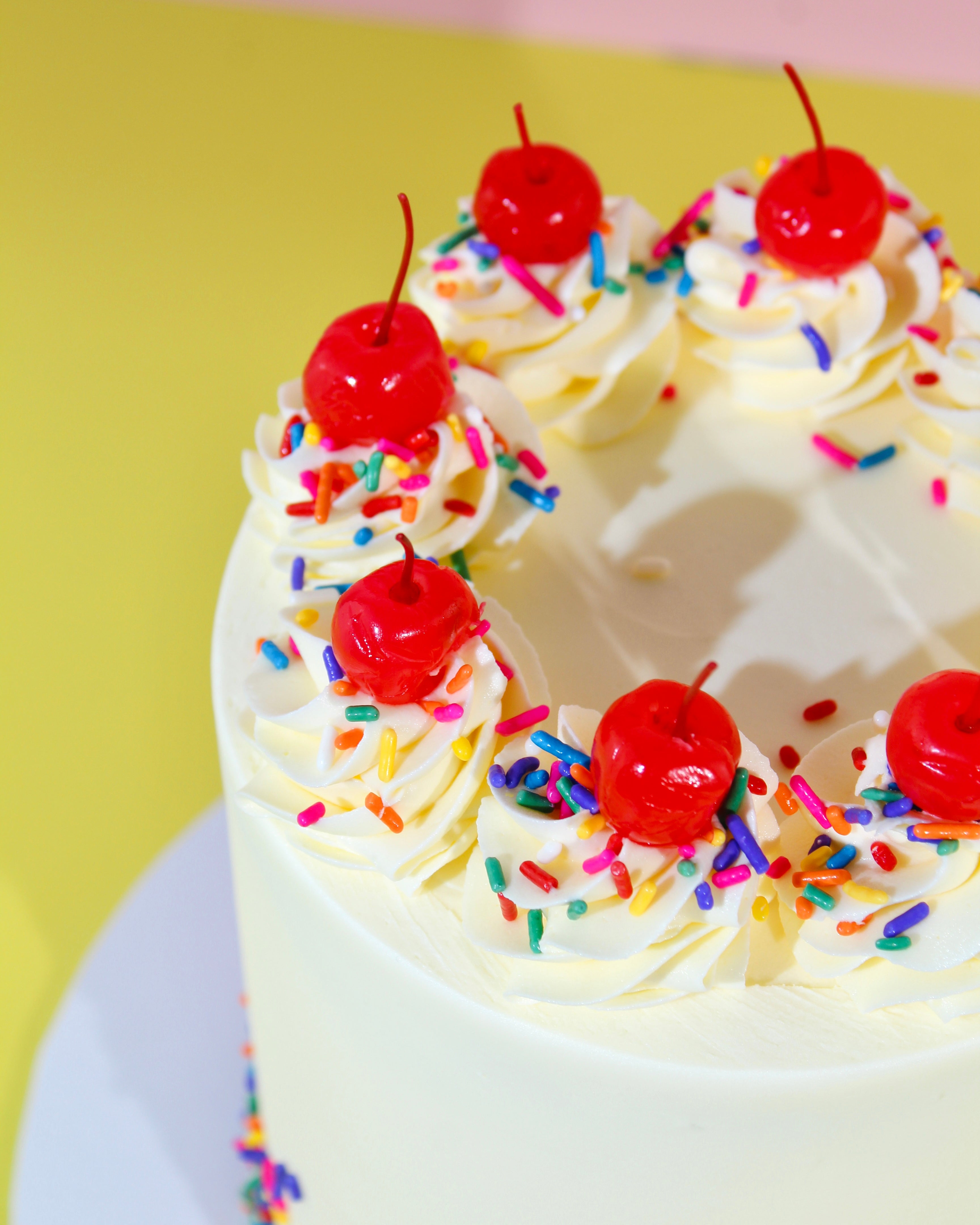 Close up of vanilla sprinkle cake with buttercream swirls and rainbow sprinkles