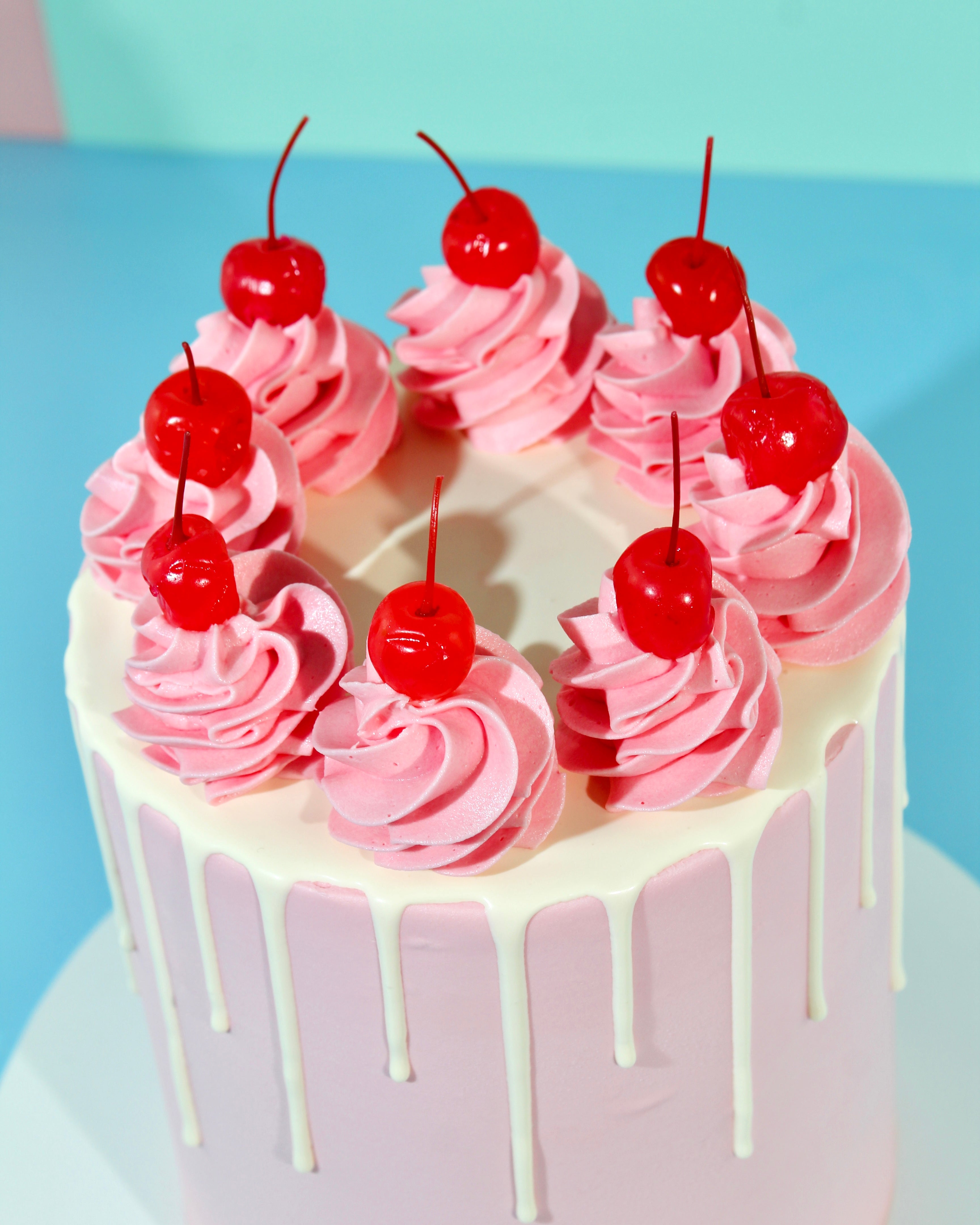 Top view of pink swirl cake with buttercream rosettes and cherries arranged in a ring