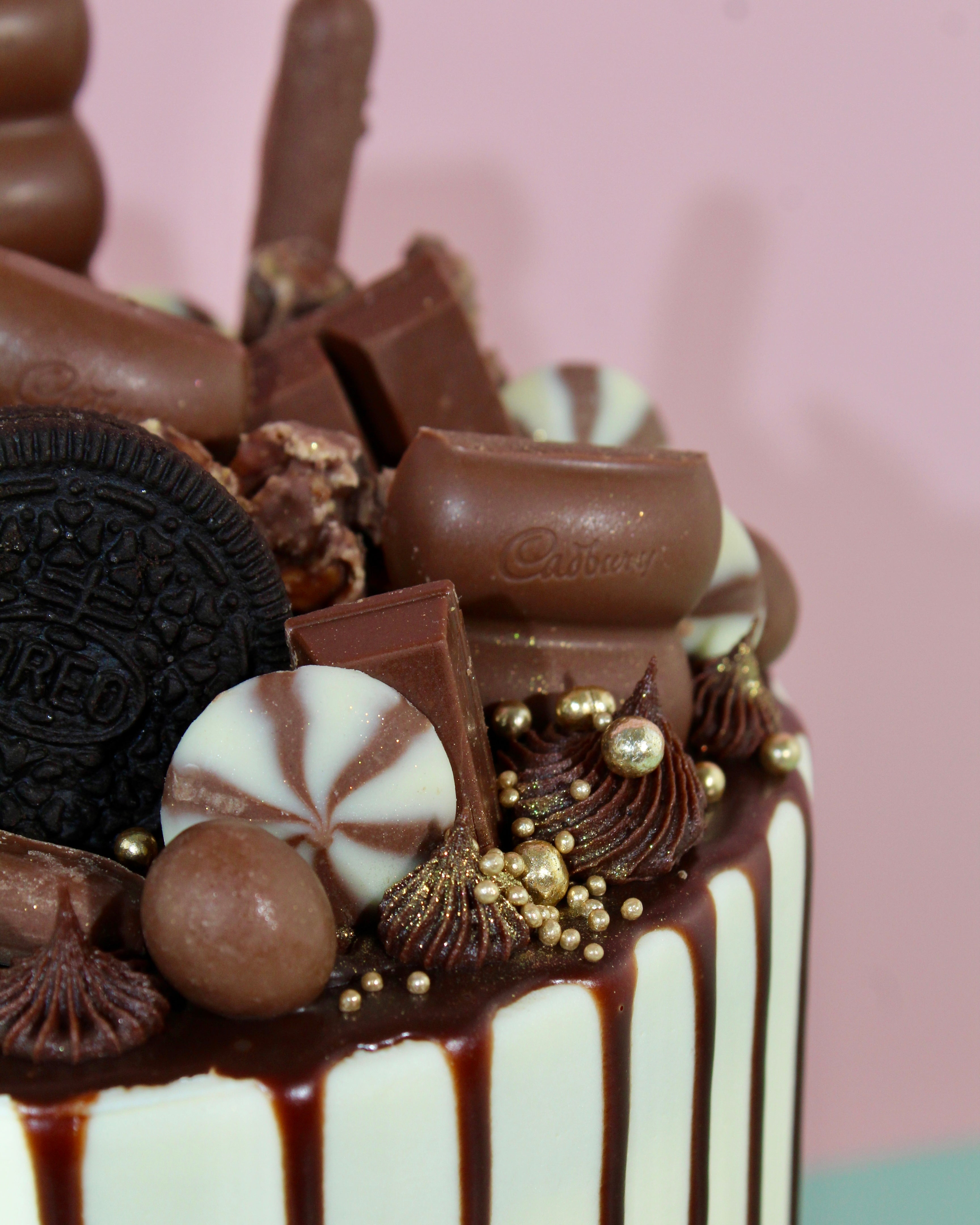 Close-up of a dessert with chocolate, cookies, and candy on a pink background
