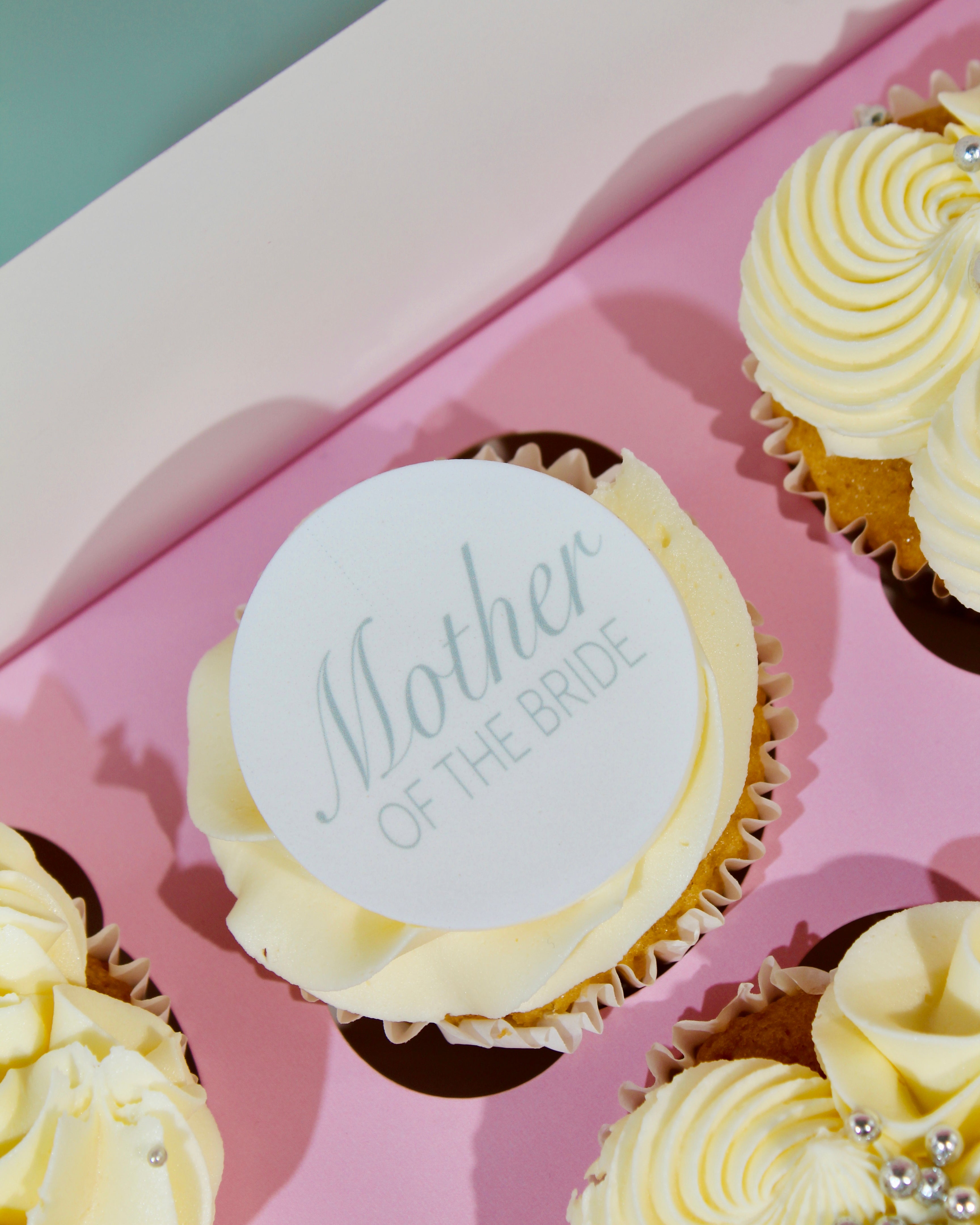 Elegant mother of the bride cupcake with ivory buttercream and edible topper on pink presentation box