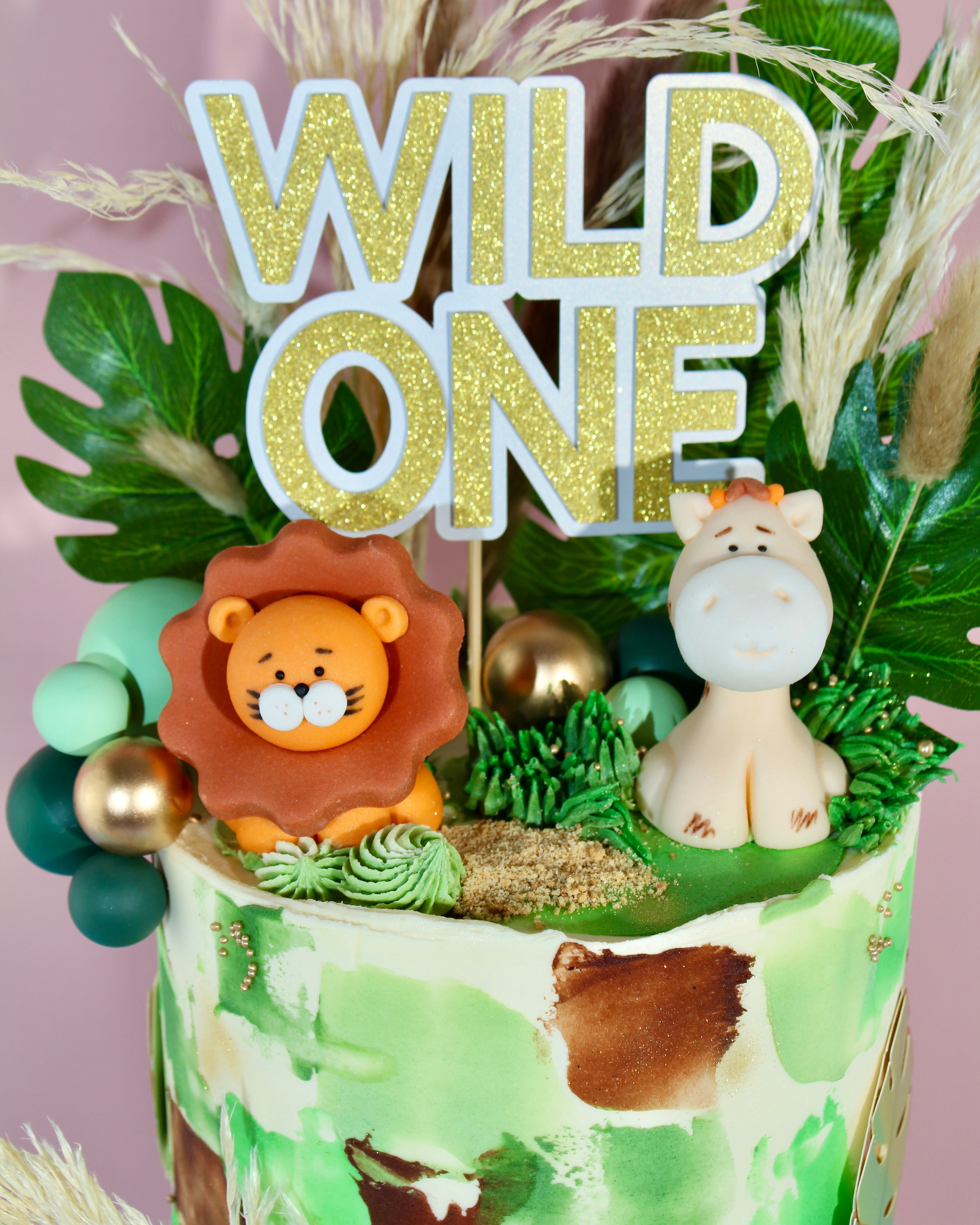 Handcrafted lion, giraffe, monkey and elephant figurines on jungle themed birthday cake
