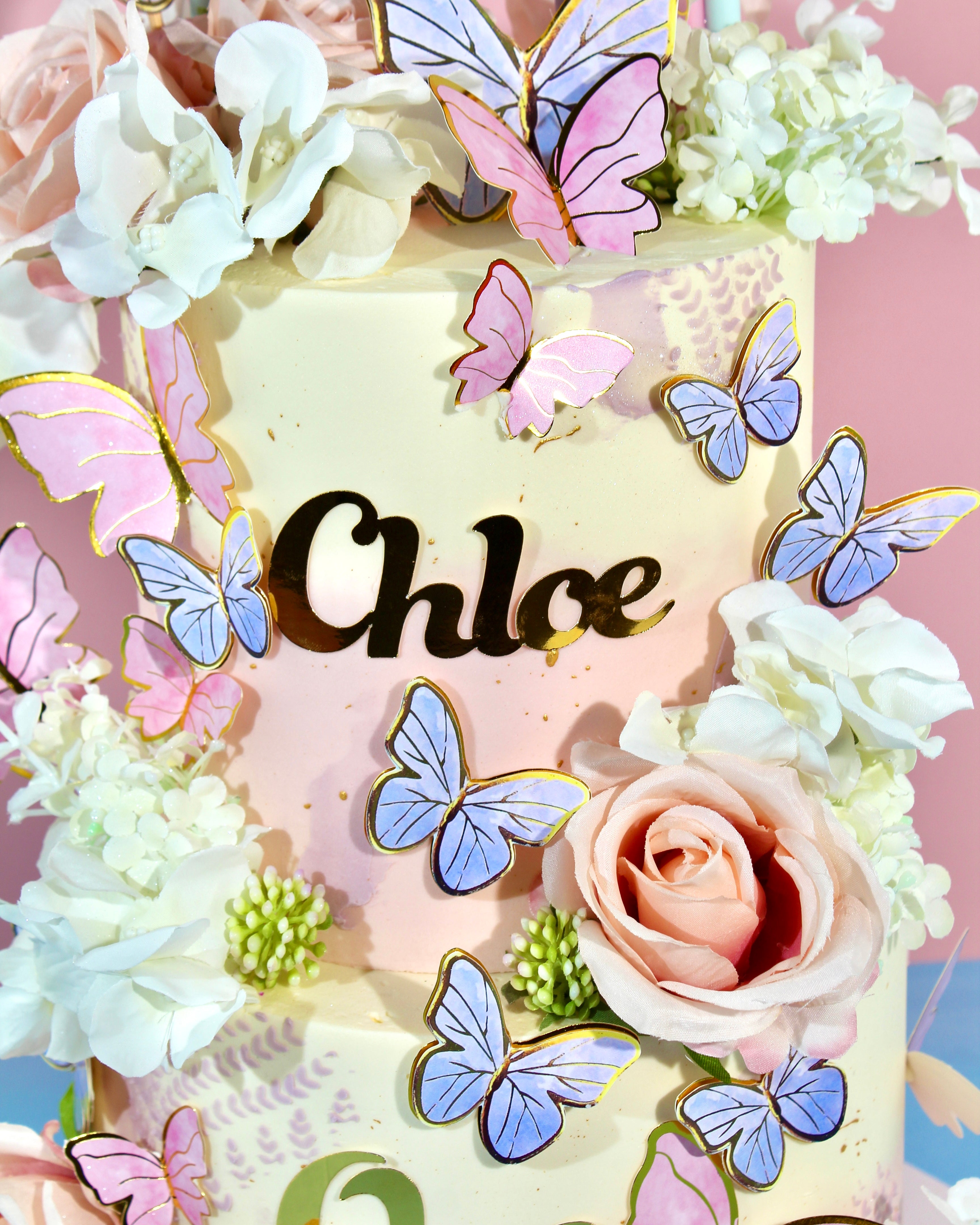 Decorative cake with butterflies and flowers on a pink background