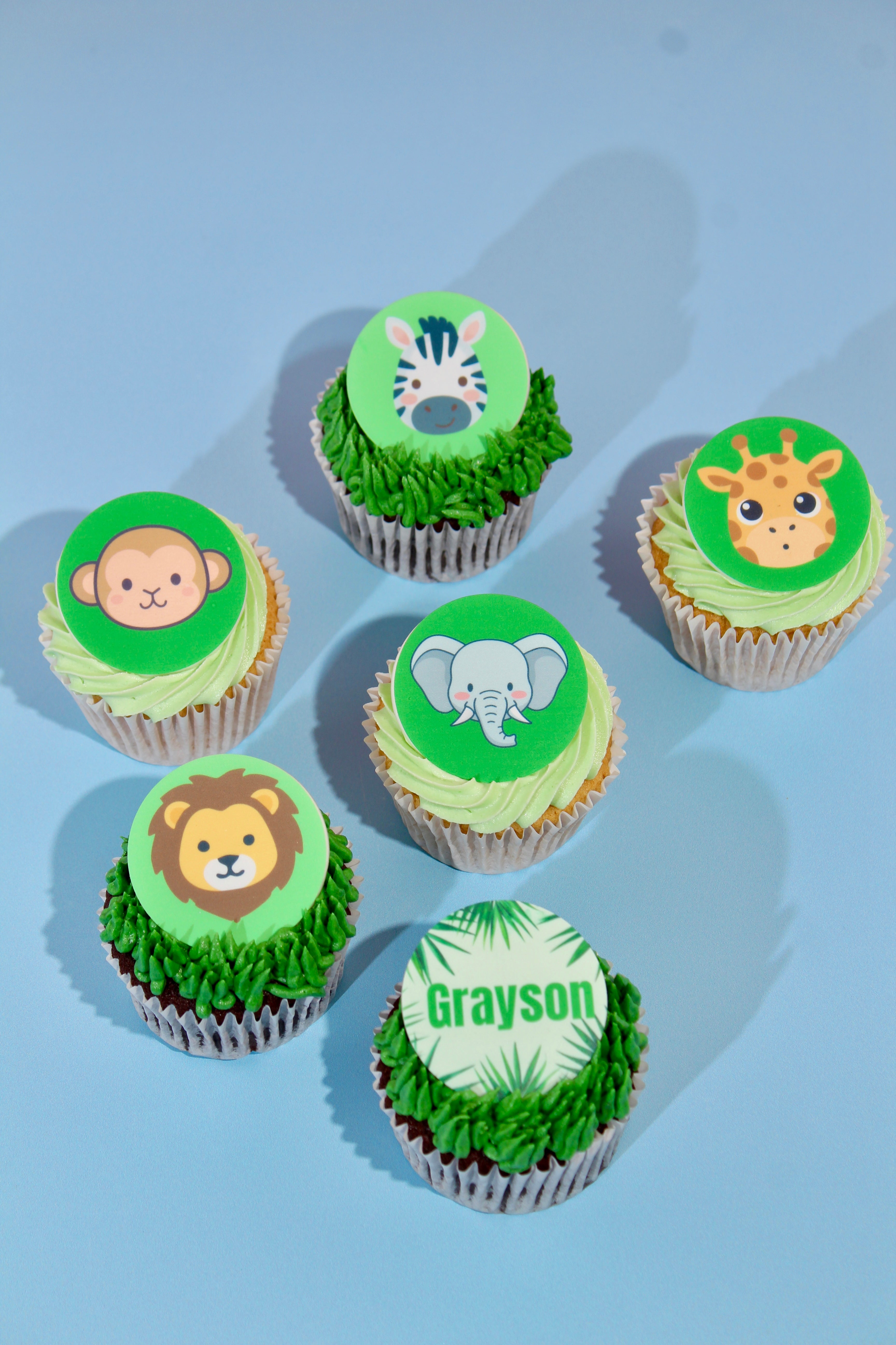 Cupcakes with animal-themed toppers on a light blue background