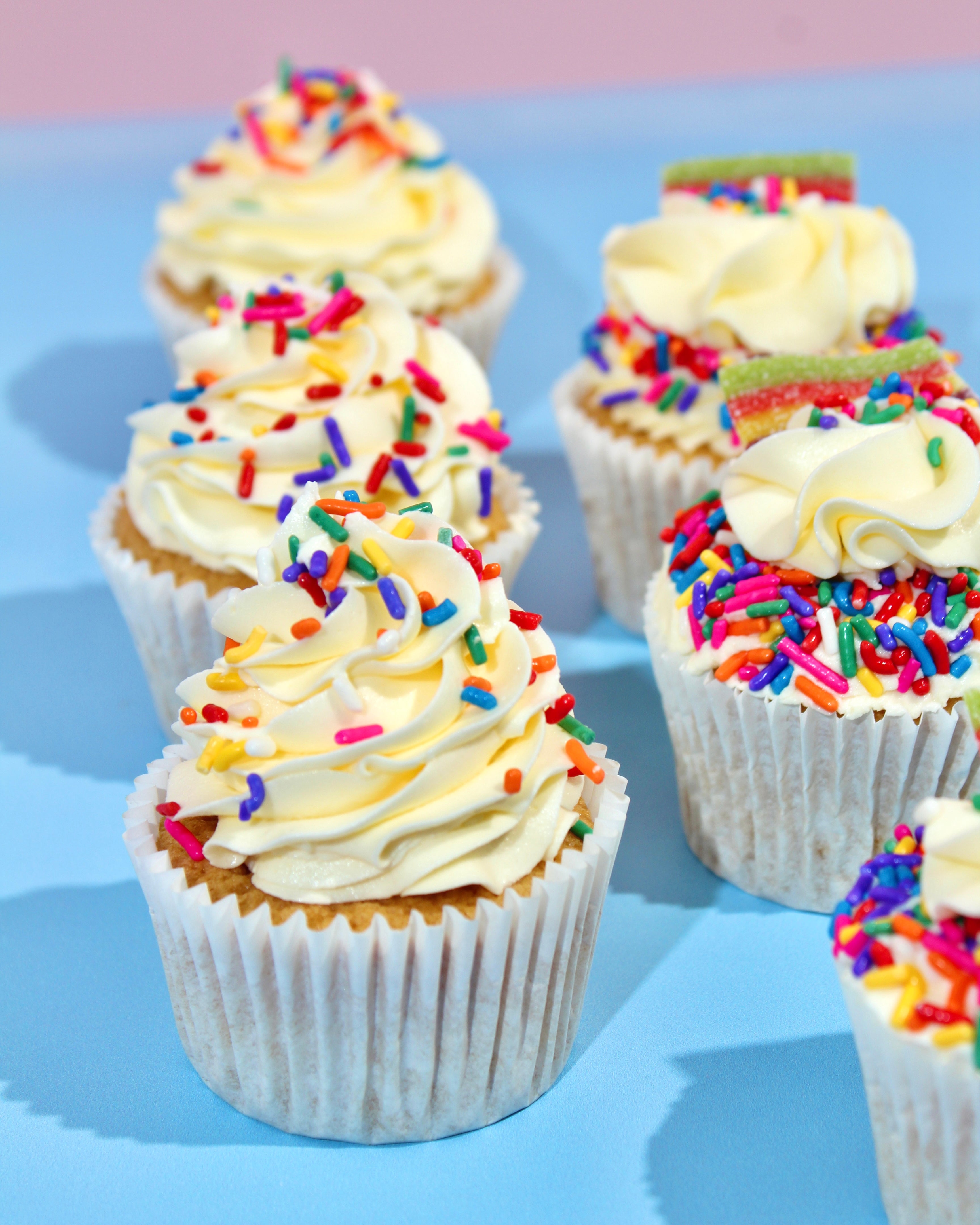 Cupcakes with white frosting and colorful sprinkles on a blue background
