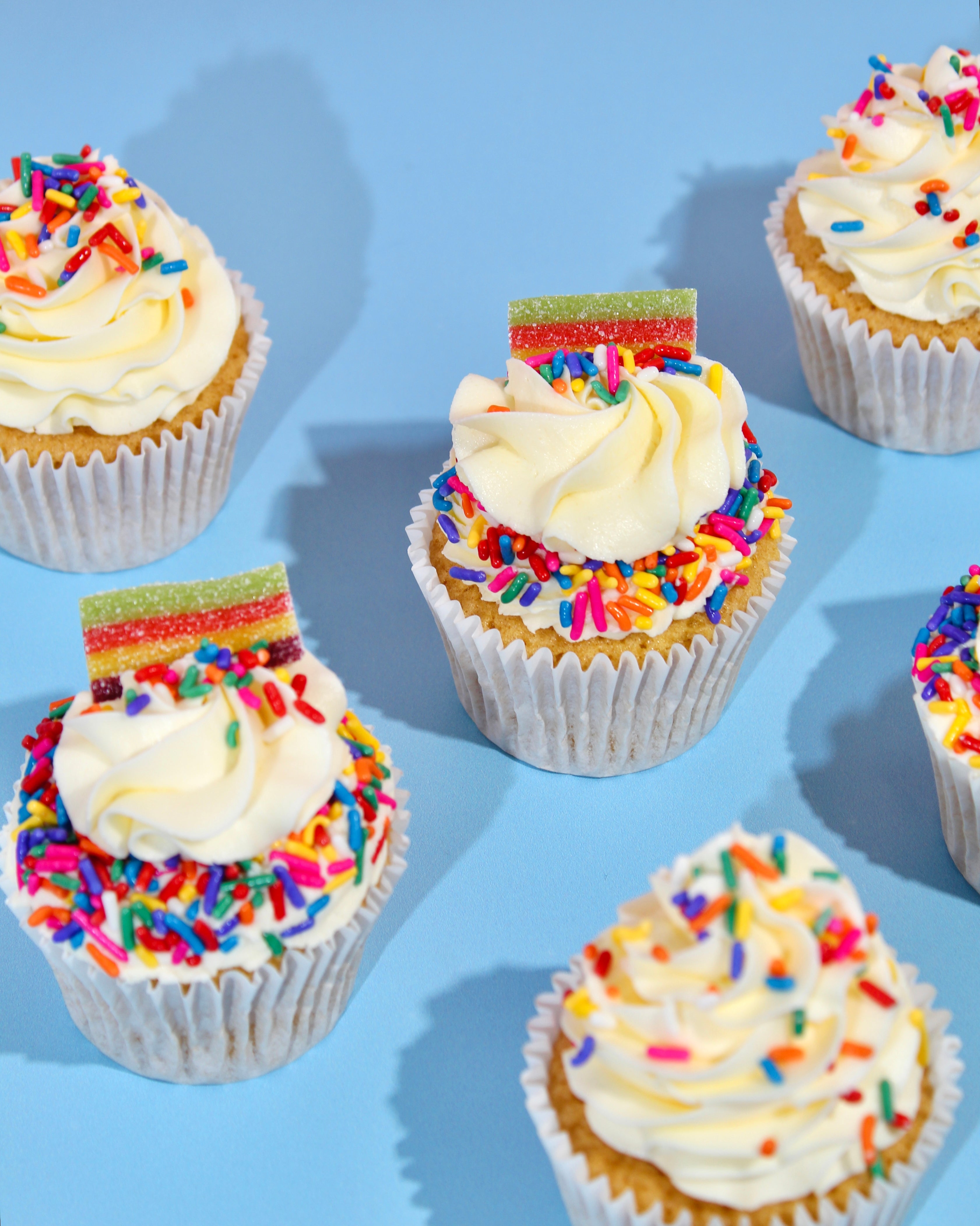 Cupcakes with white frosting and colorful sprinkles on a blue background