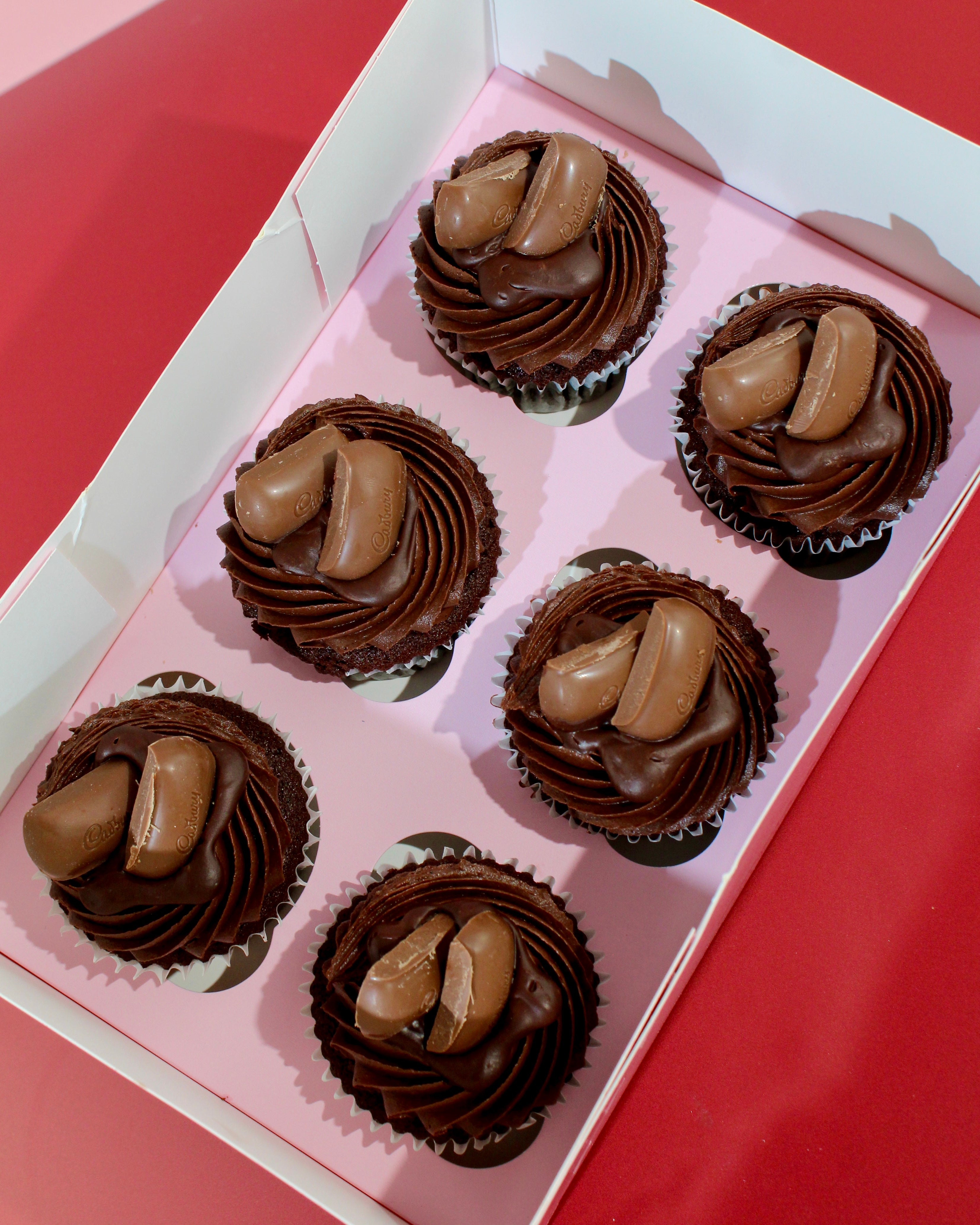 Box of triple chocolate cupcakes with chocolate buttercream and chocolate pieces on top
