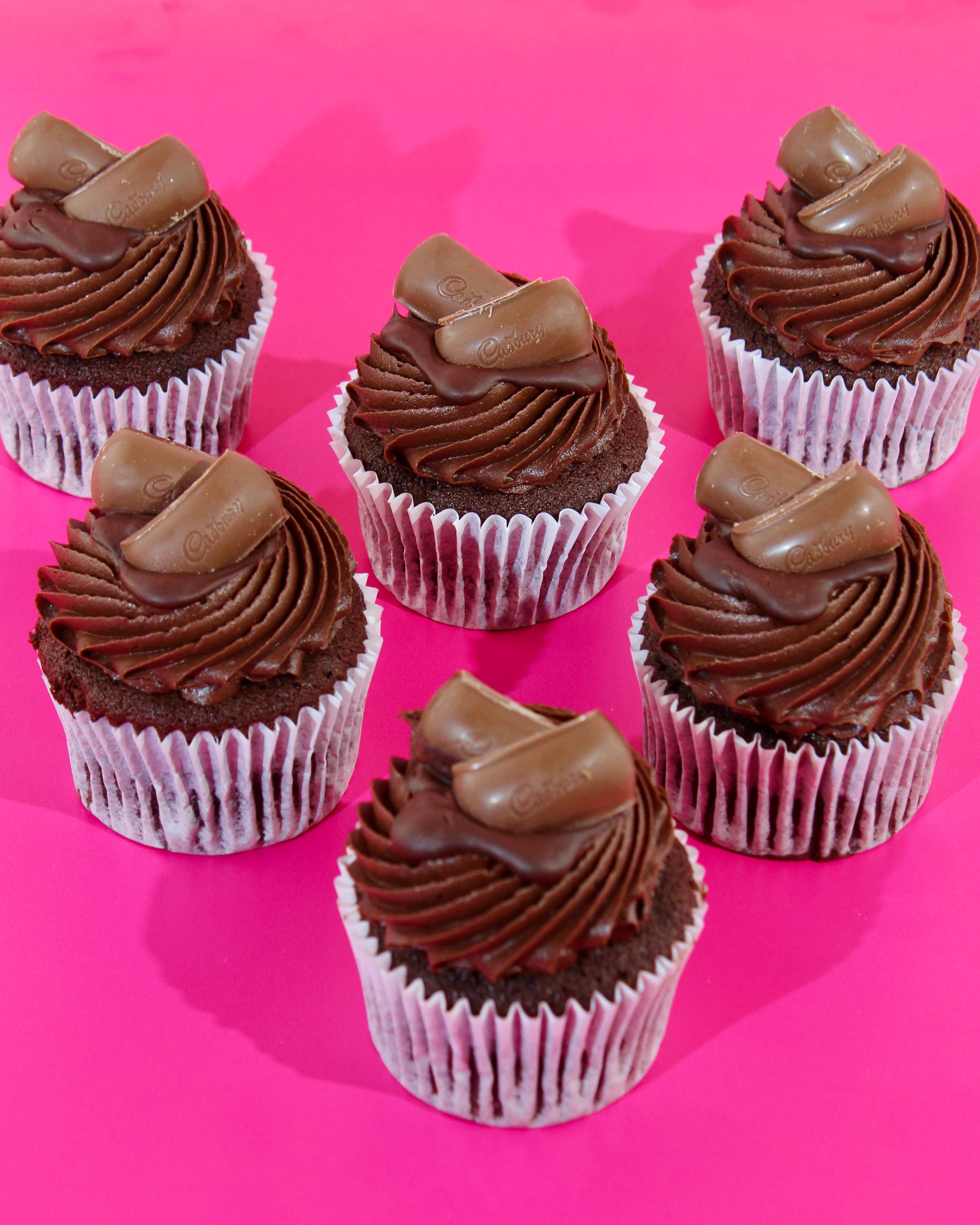 Triple chocolate cupcakes arranged on pink background