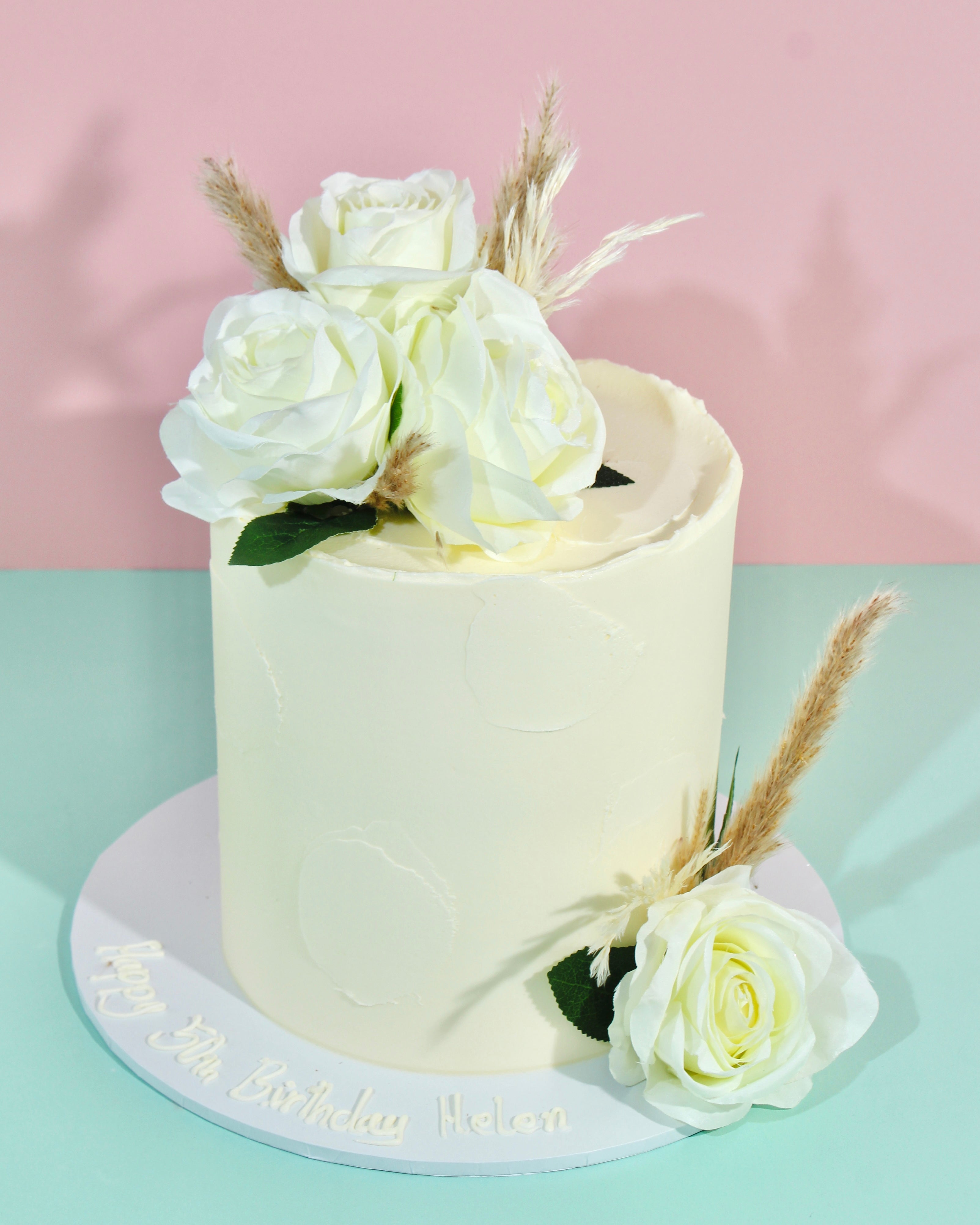 Elegant boho birthday cake with personalised iced message on cake board, white floral decoration