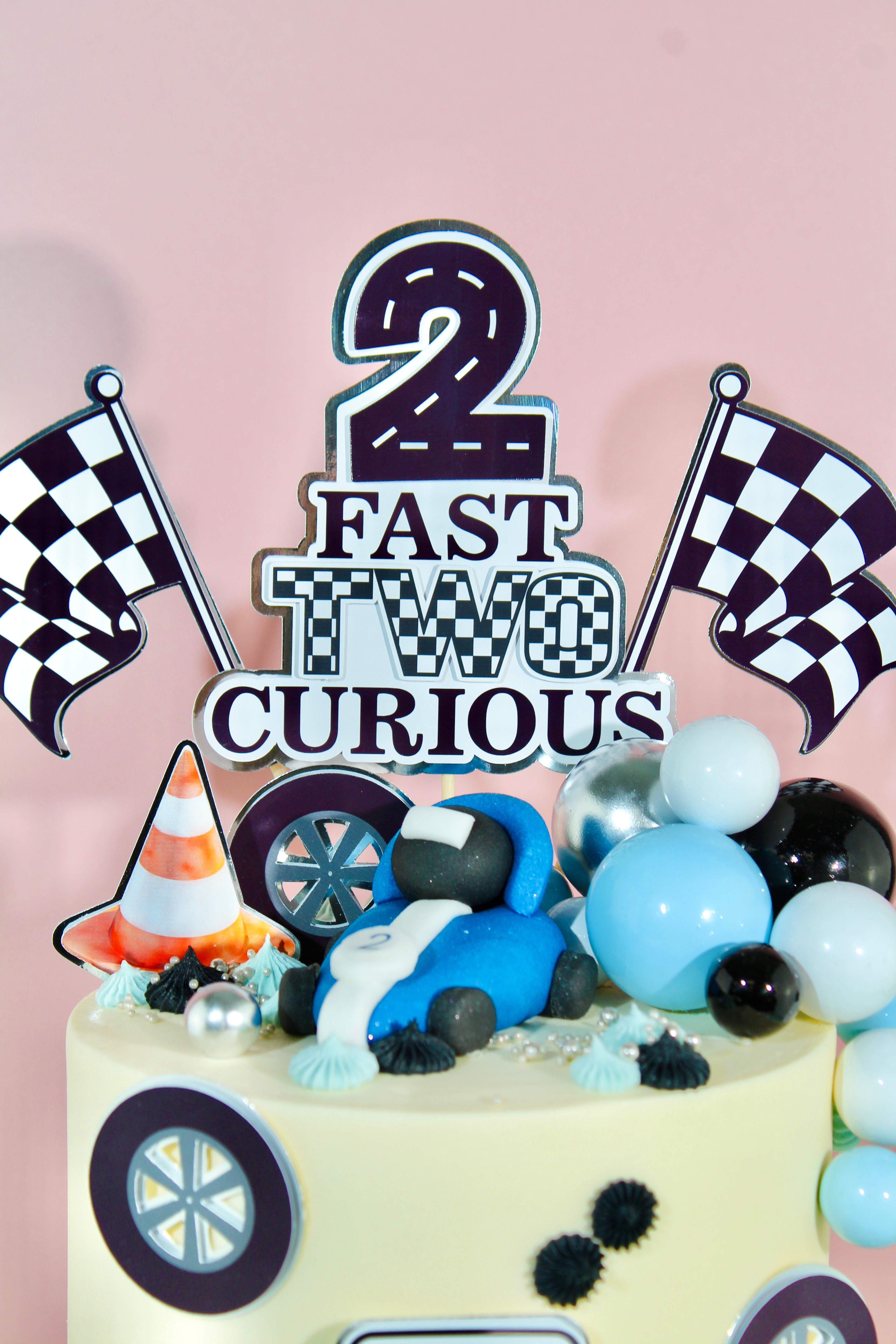Chequered number 2, traffic cones and miniature race cars on racing themed birthday cake