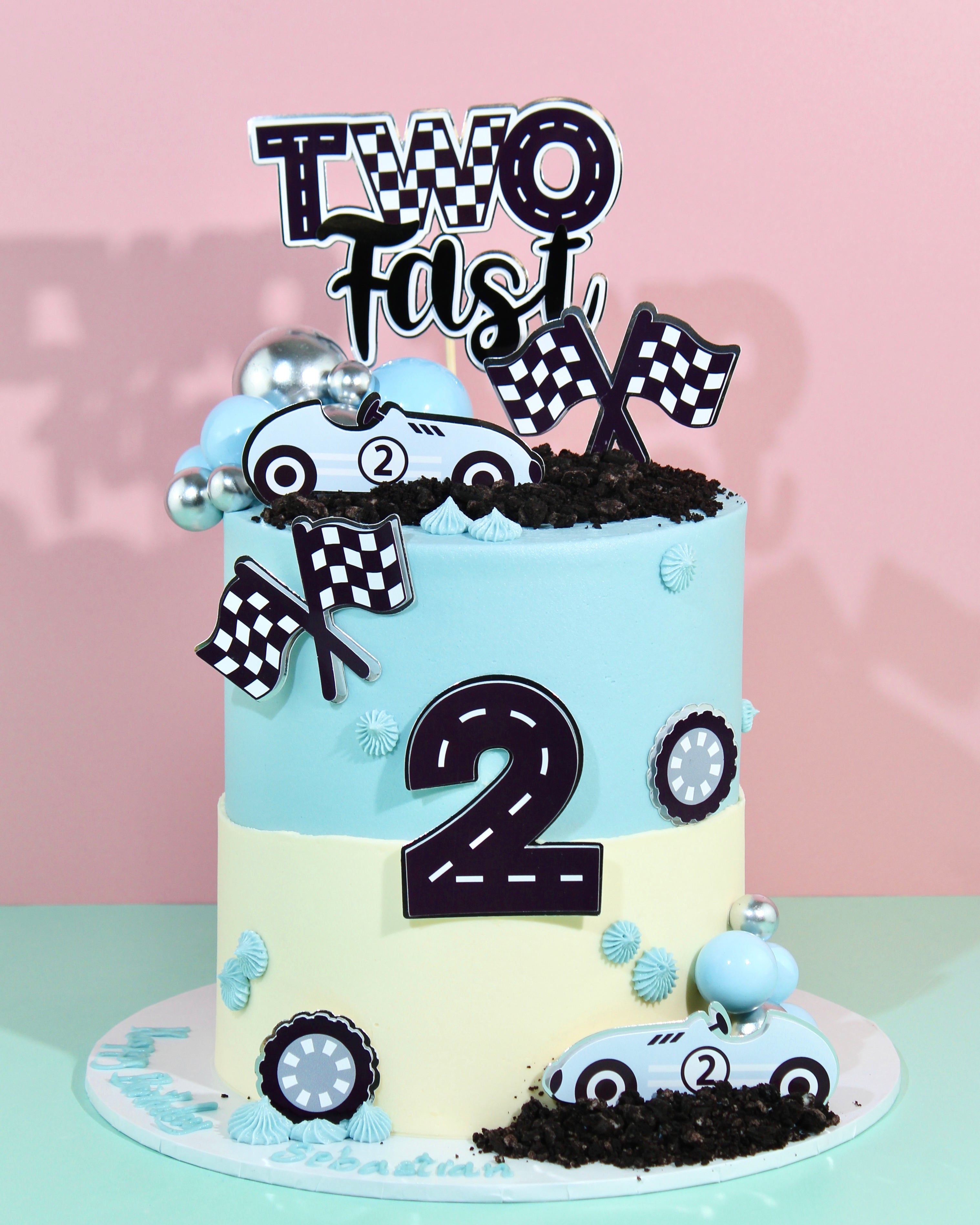 Baby blue racing birthday cake with chequered flags and Two Fast topper
