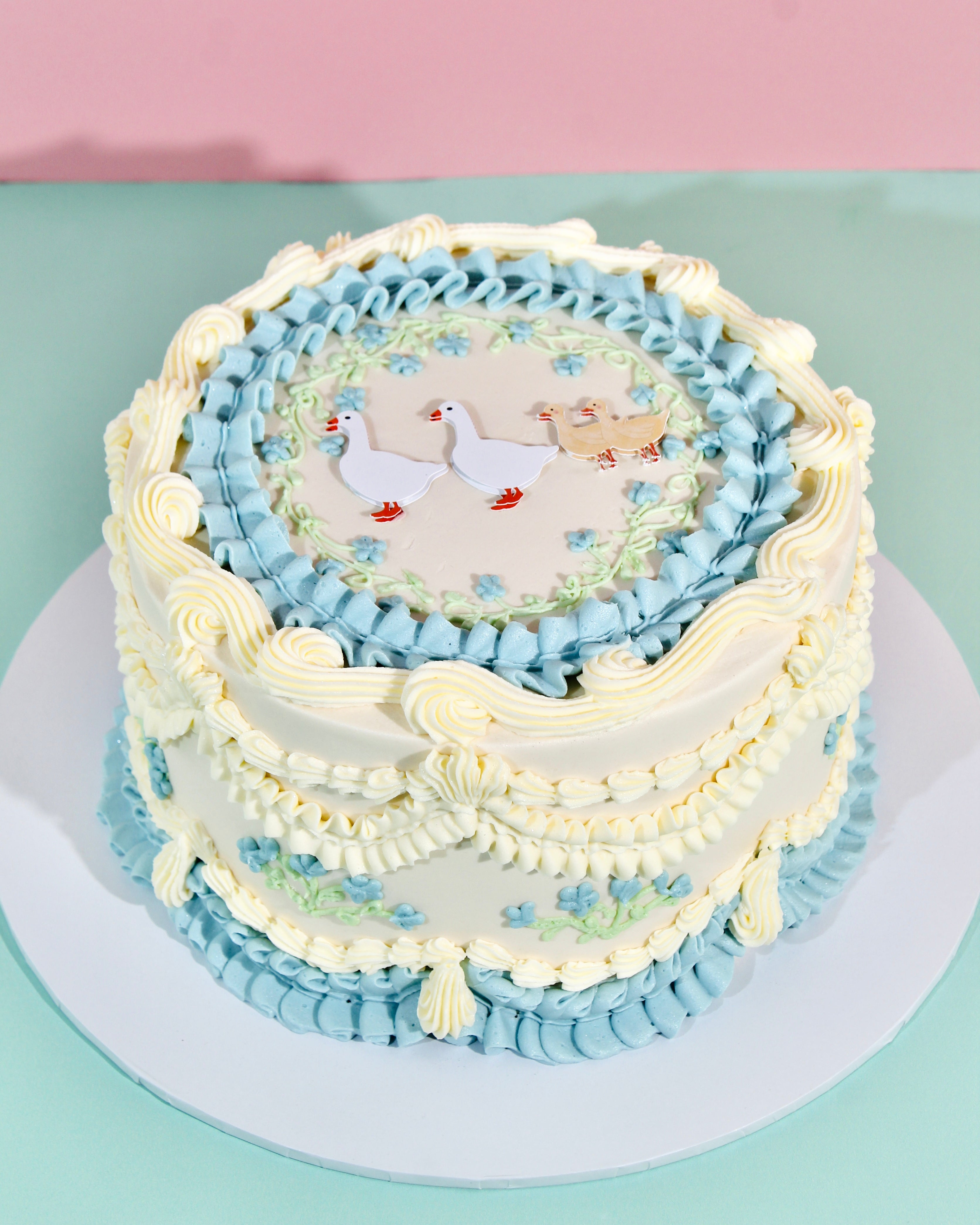 Vintage style baby blue and ivory buttercream cake with duckling family scene on top