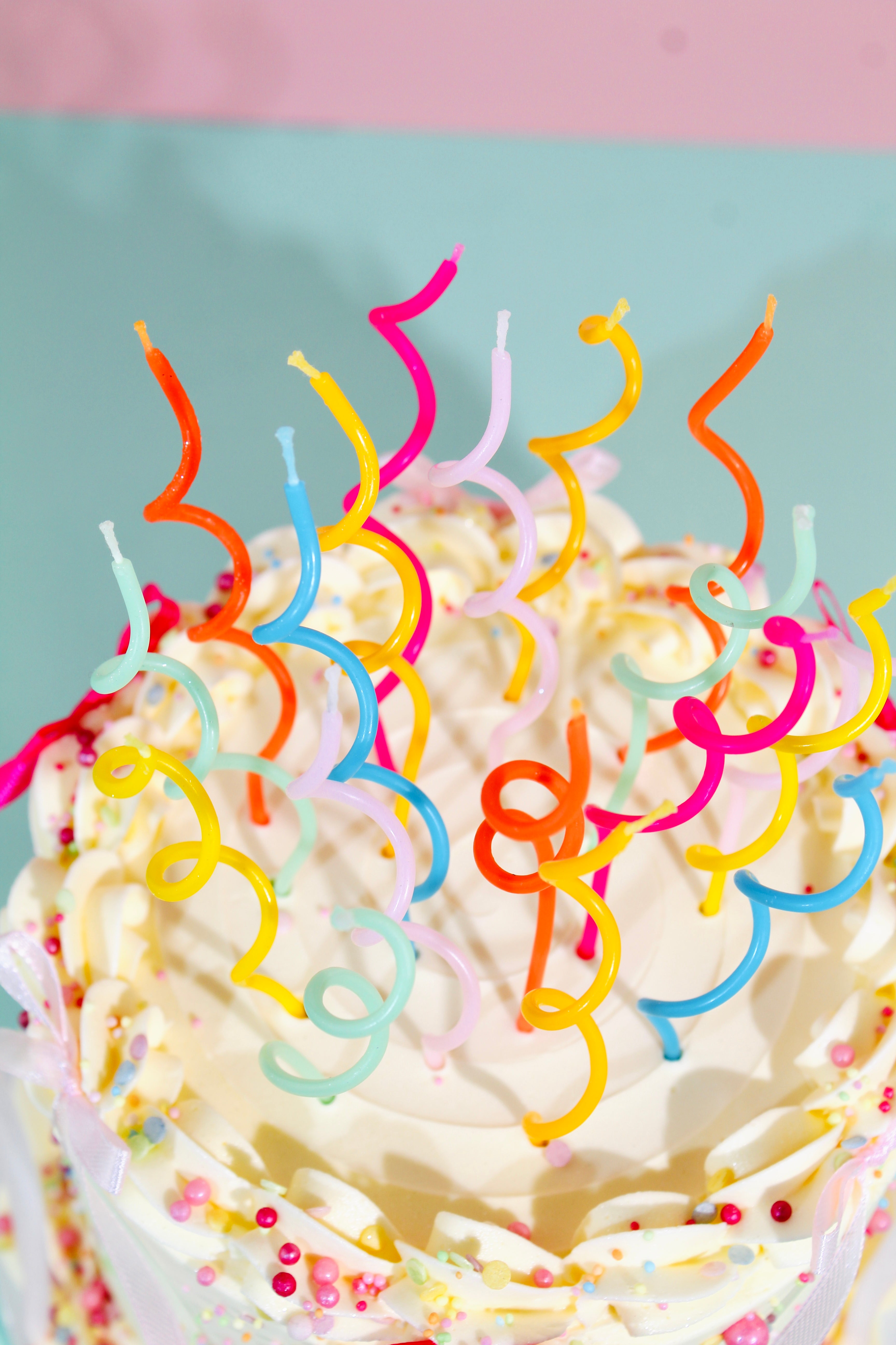 Close-up of a cake with colorful curly candles on a light blue background