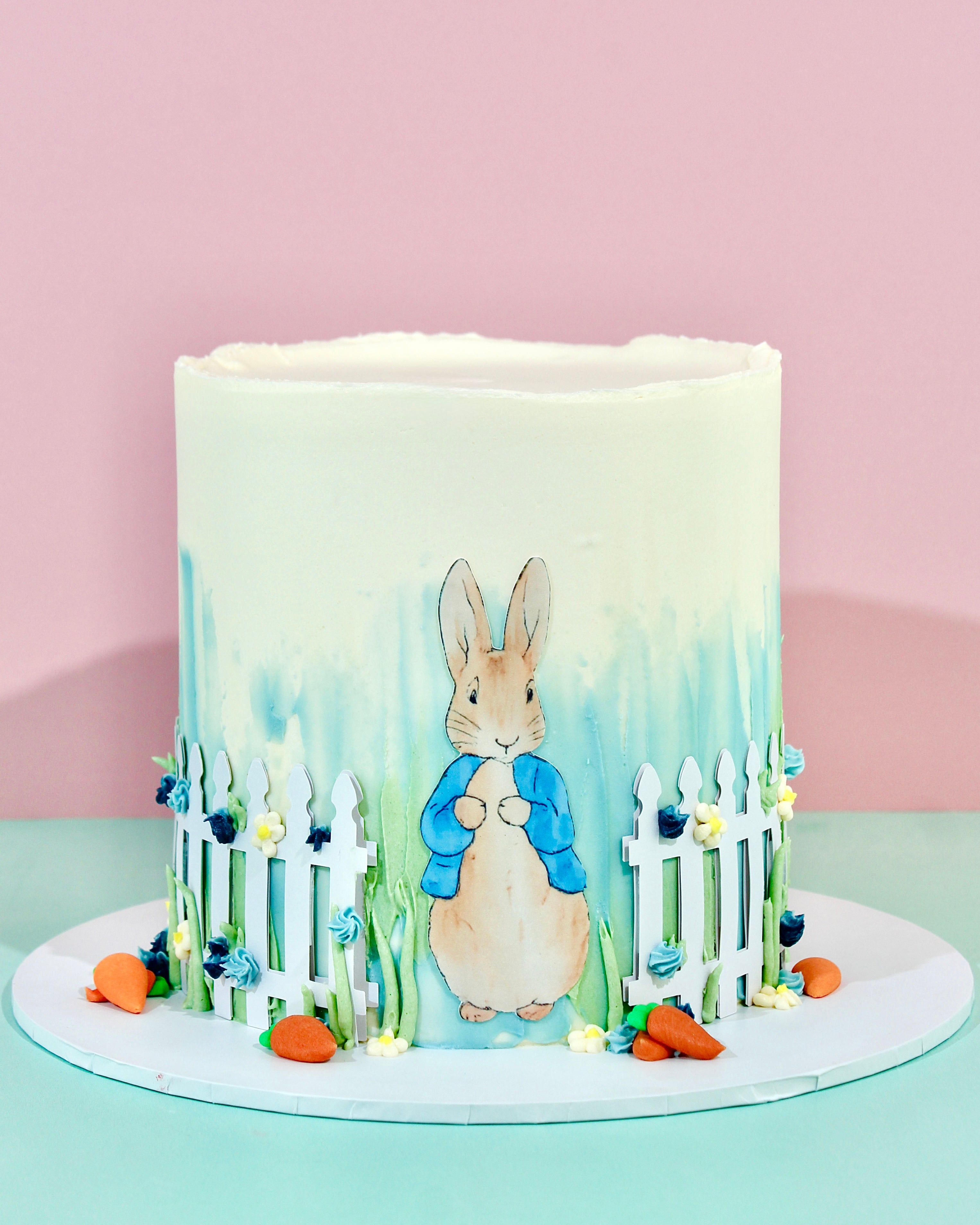Garden rabbit birthday cake with watercolour buttercream, white picket fence and carrot decorations