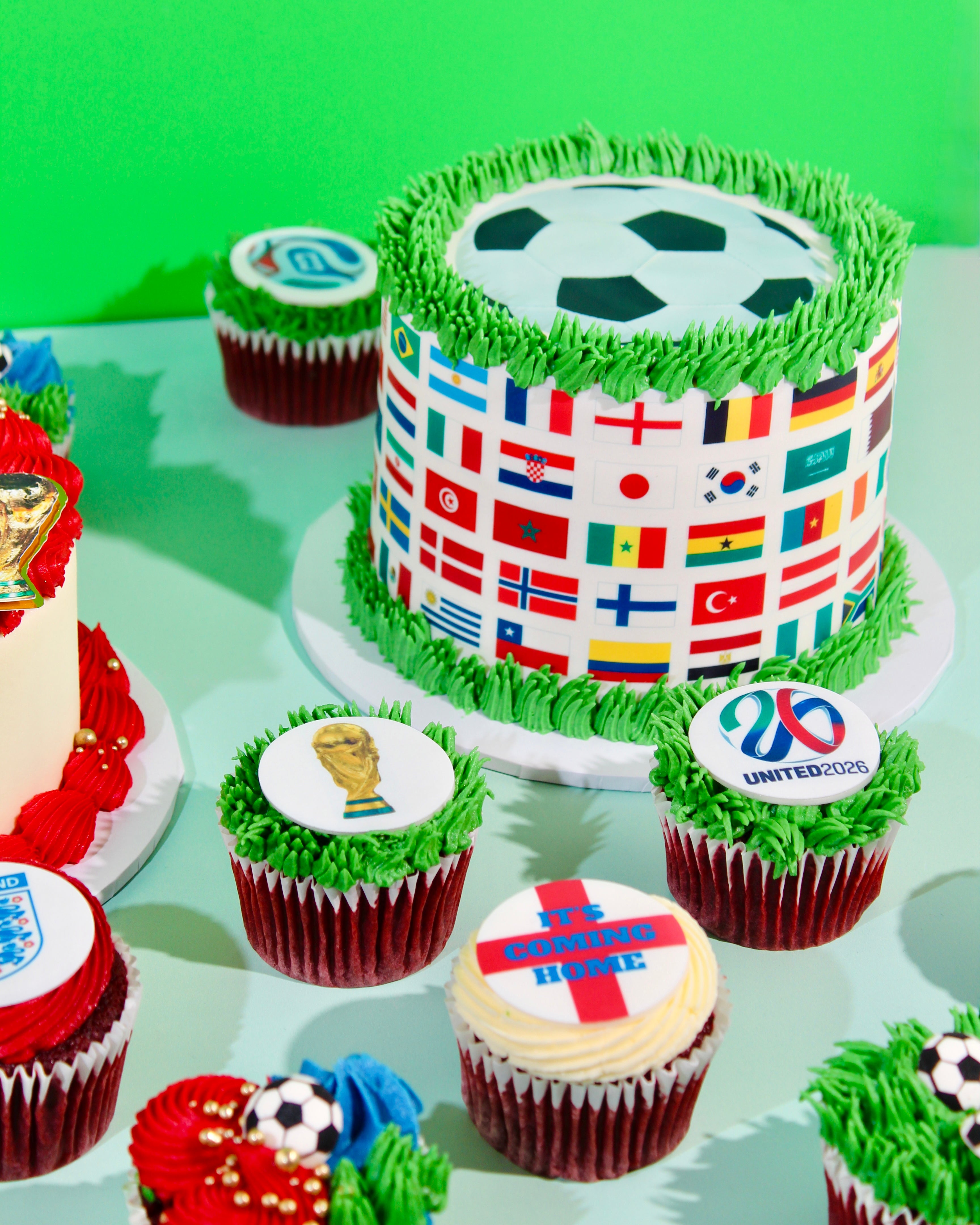 World Cup celebration cake wrapped in international flags with green grass buttercream and football topper