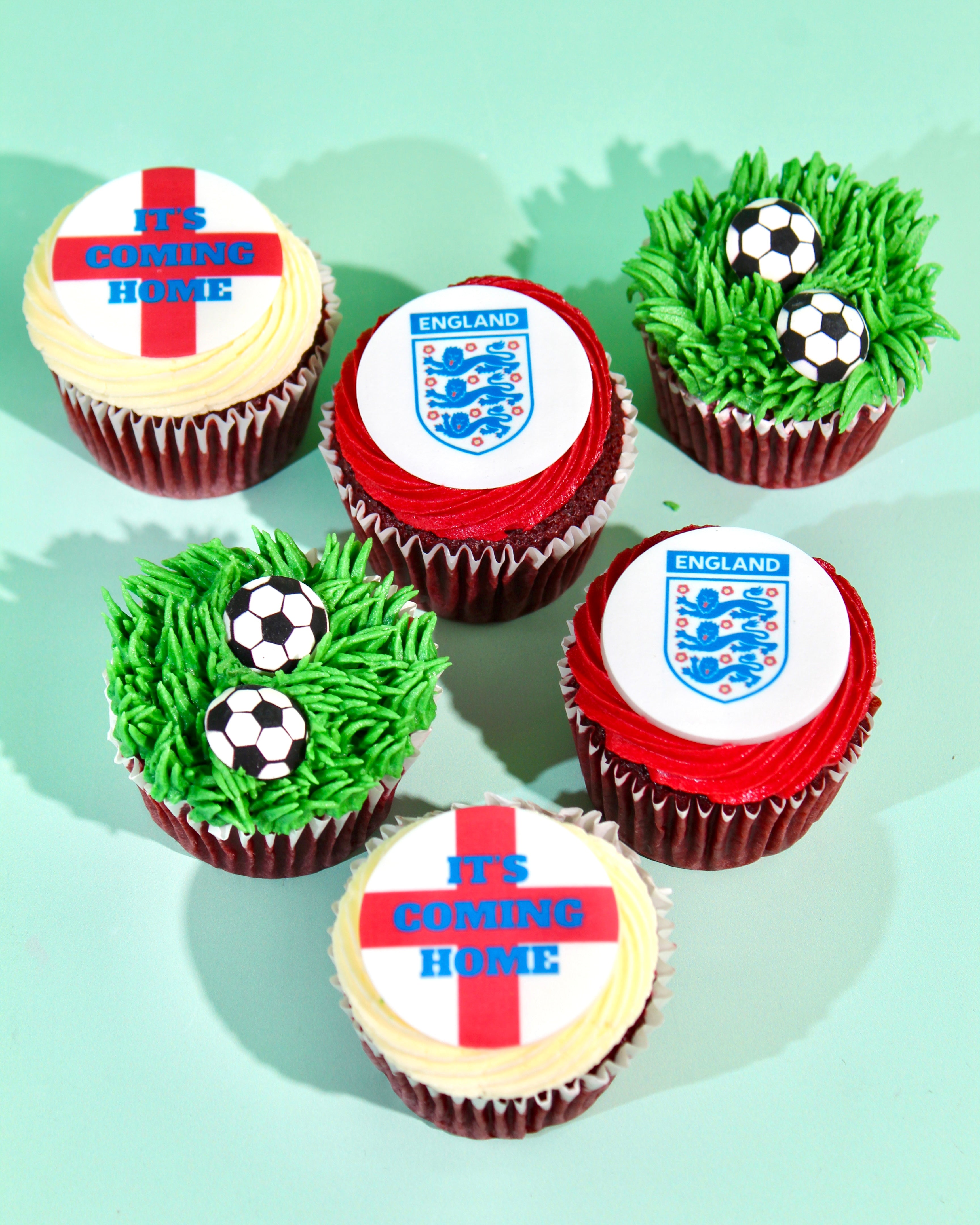Close-up of England Three Lions badge and St George's Cross cupcake toppers with red and green buttercream

