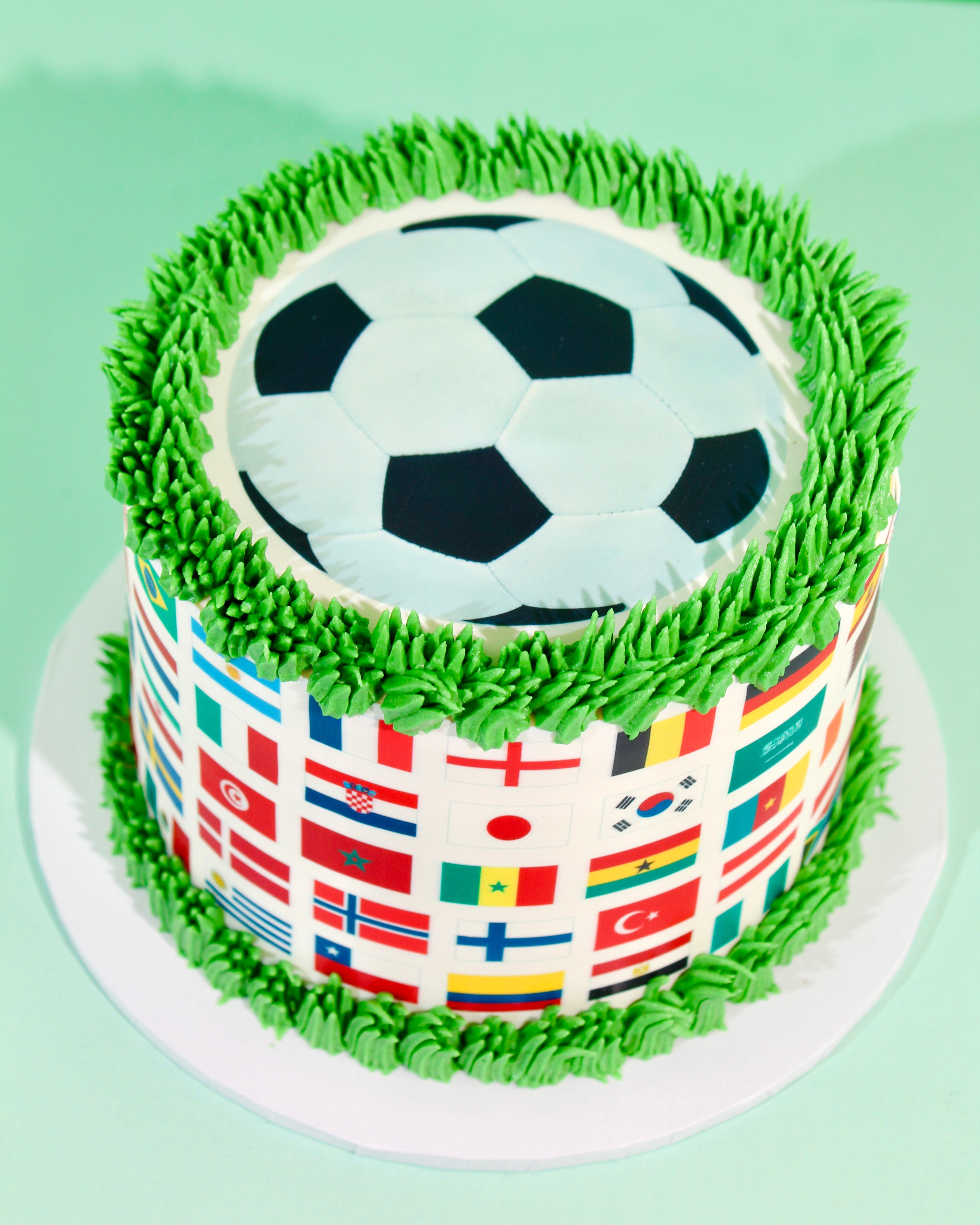 Top view of World Cup cake showing sculpted fondant football surrounded by hand-piped green grass buttercream
