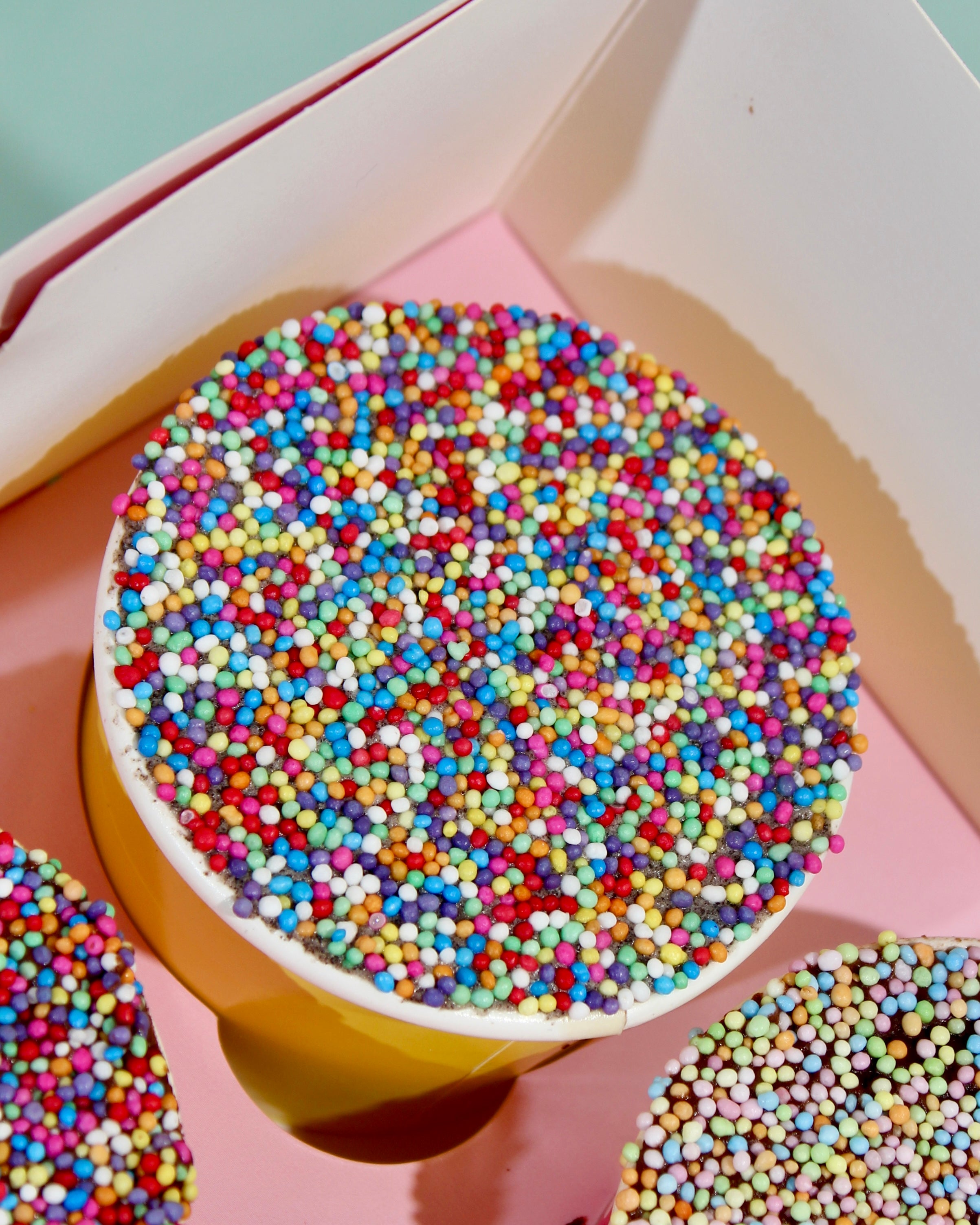 Individual rainbow dot sprinkle cake pot with colourful spoon, served in branded Amy's Bakehouse cup