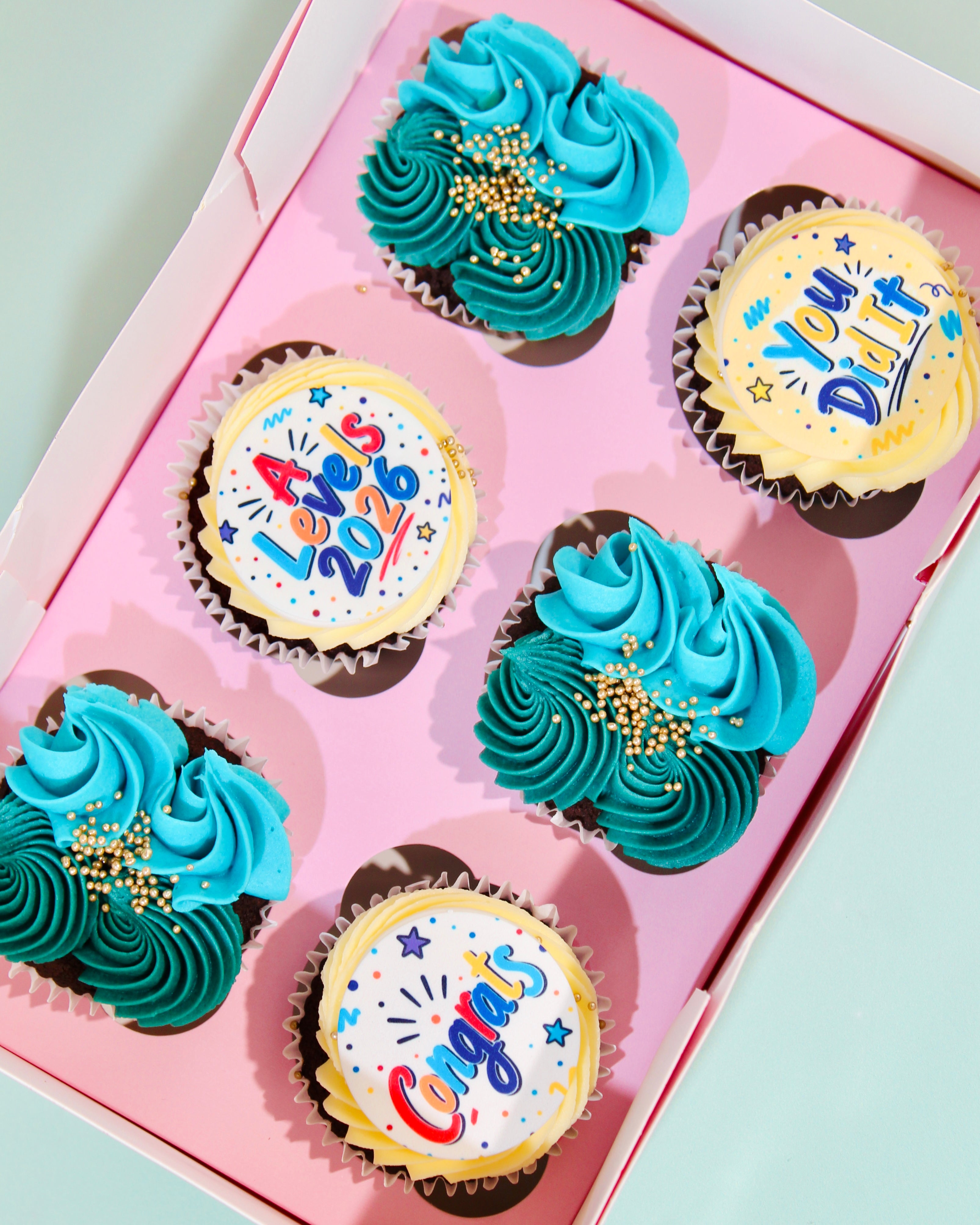 Box of six A Level 2026 cupcakes with A Levels 2026 disc, You Did It and Congrats designs in teal and blue buttercream