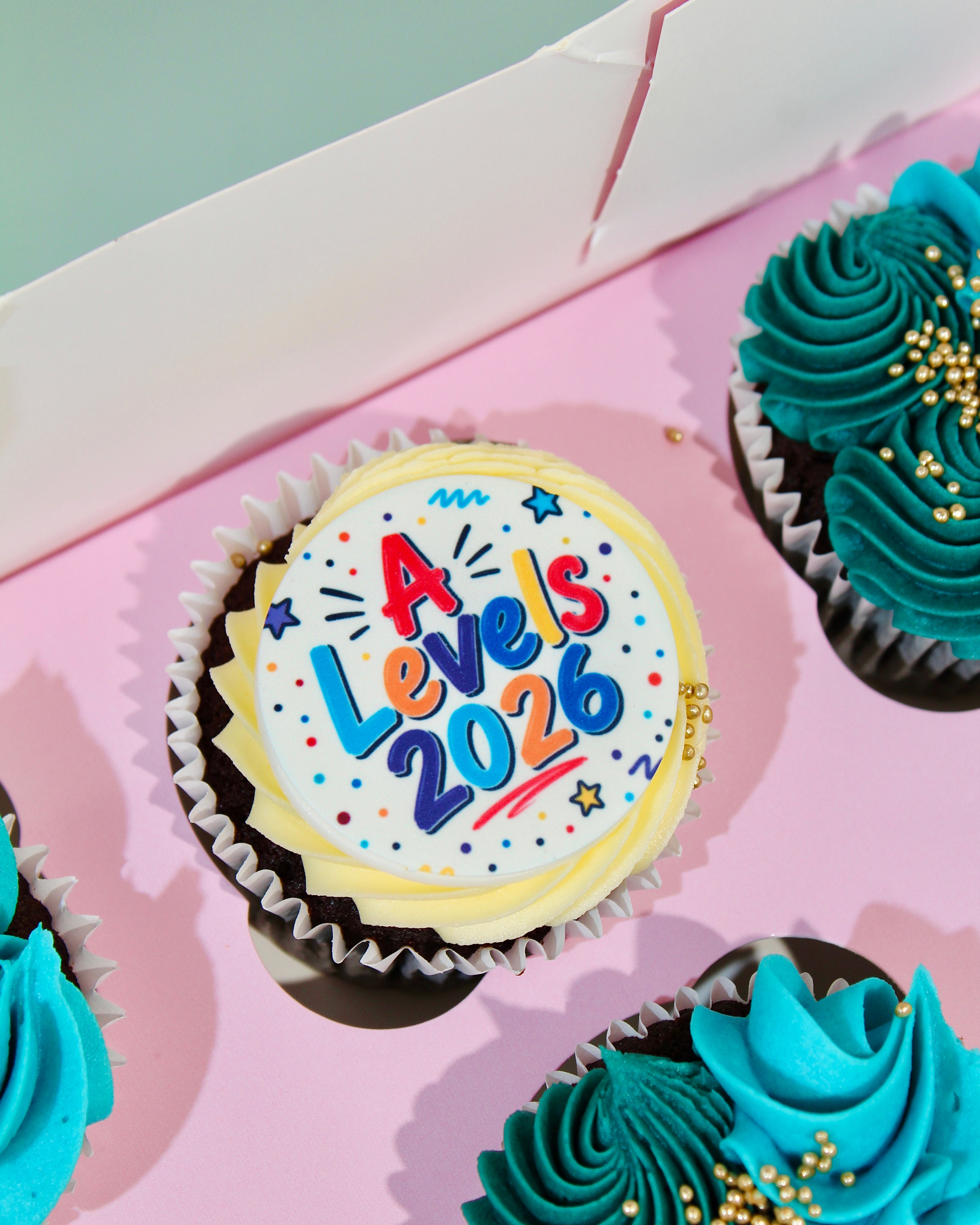 lose-up of A Levels 2026 celebration cupcake disc with colourful lettering and gold pearl detail