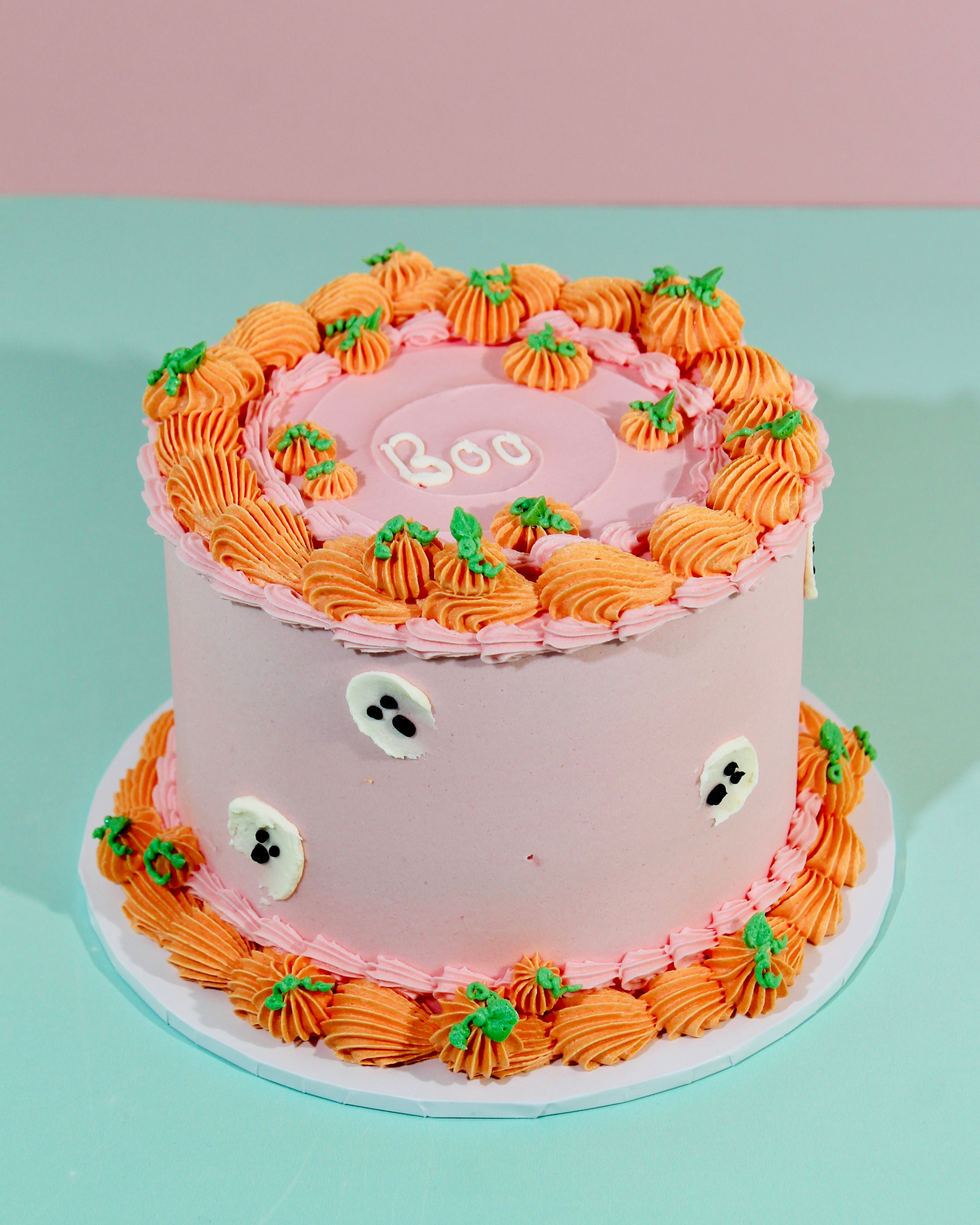 Bird's eye view of Cute Pumpkin Cake showing Boo iced message surrounded by orange pumpkin and green leaf piped rosettes