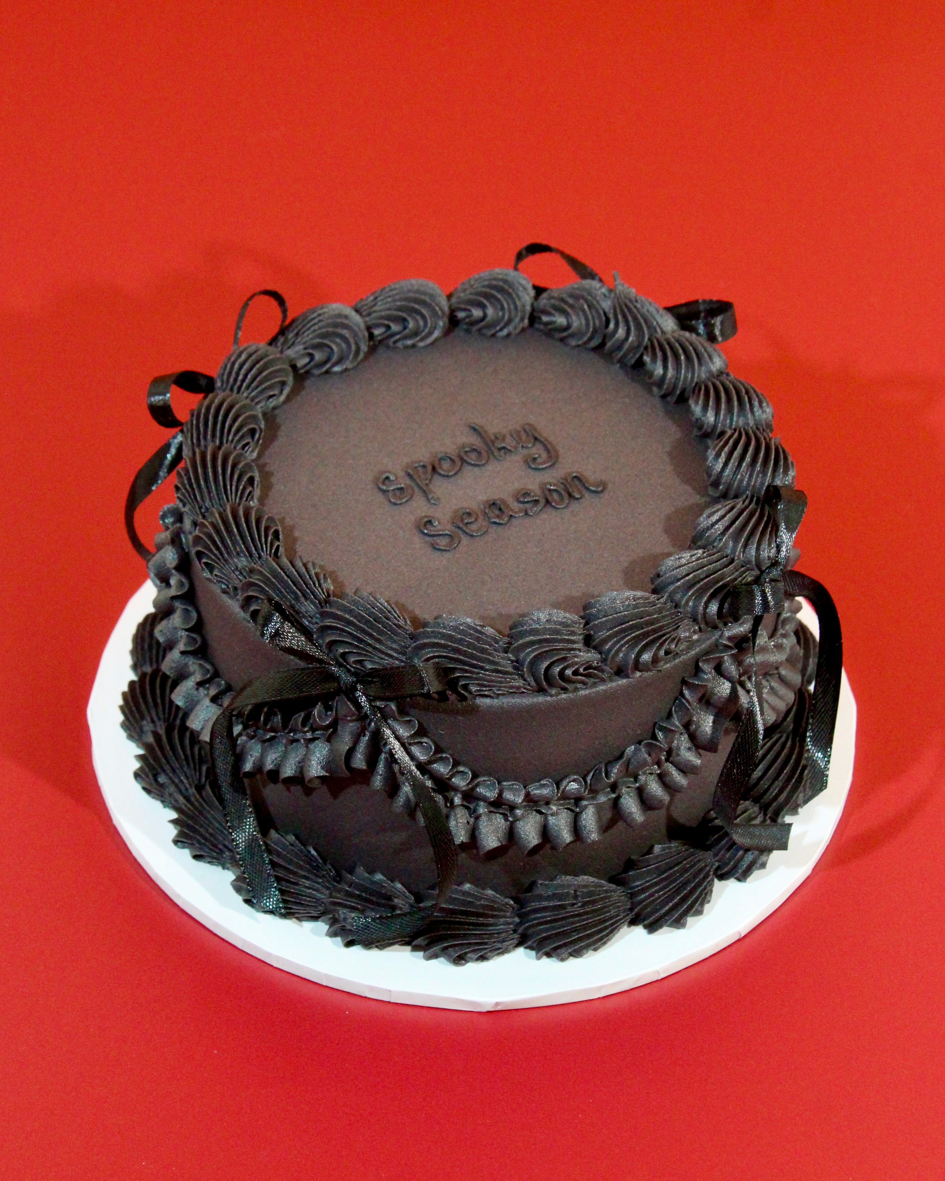 Close-up of black buttercream piped border and ribbon bow detail on all-black Midnight Halloween cake