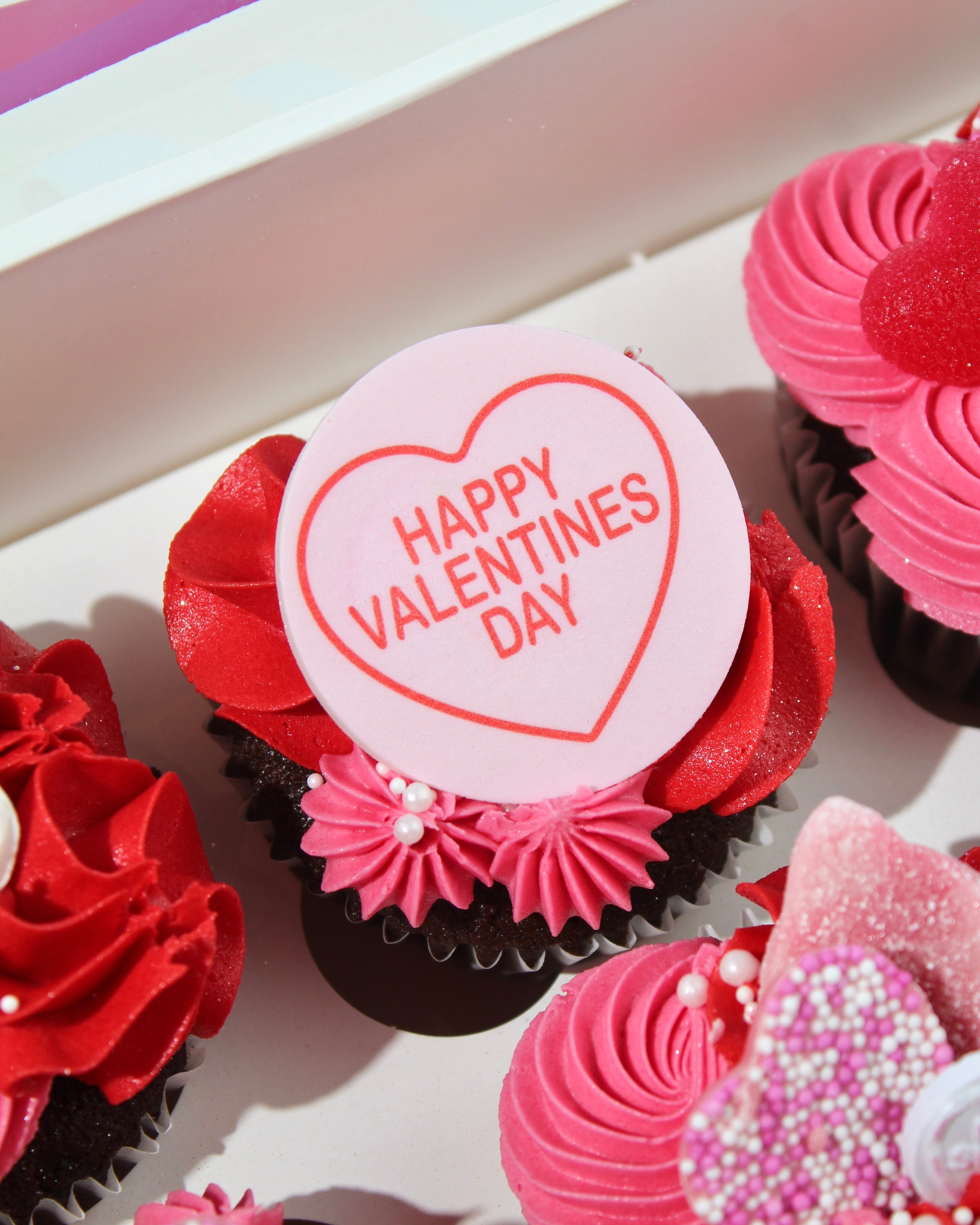 Close-up of Valentine’s cupcake with pink buttercream, red icing and heart decorations