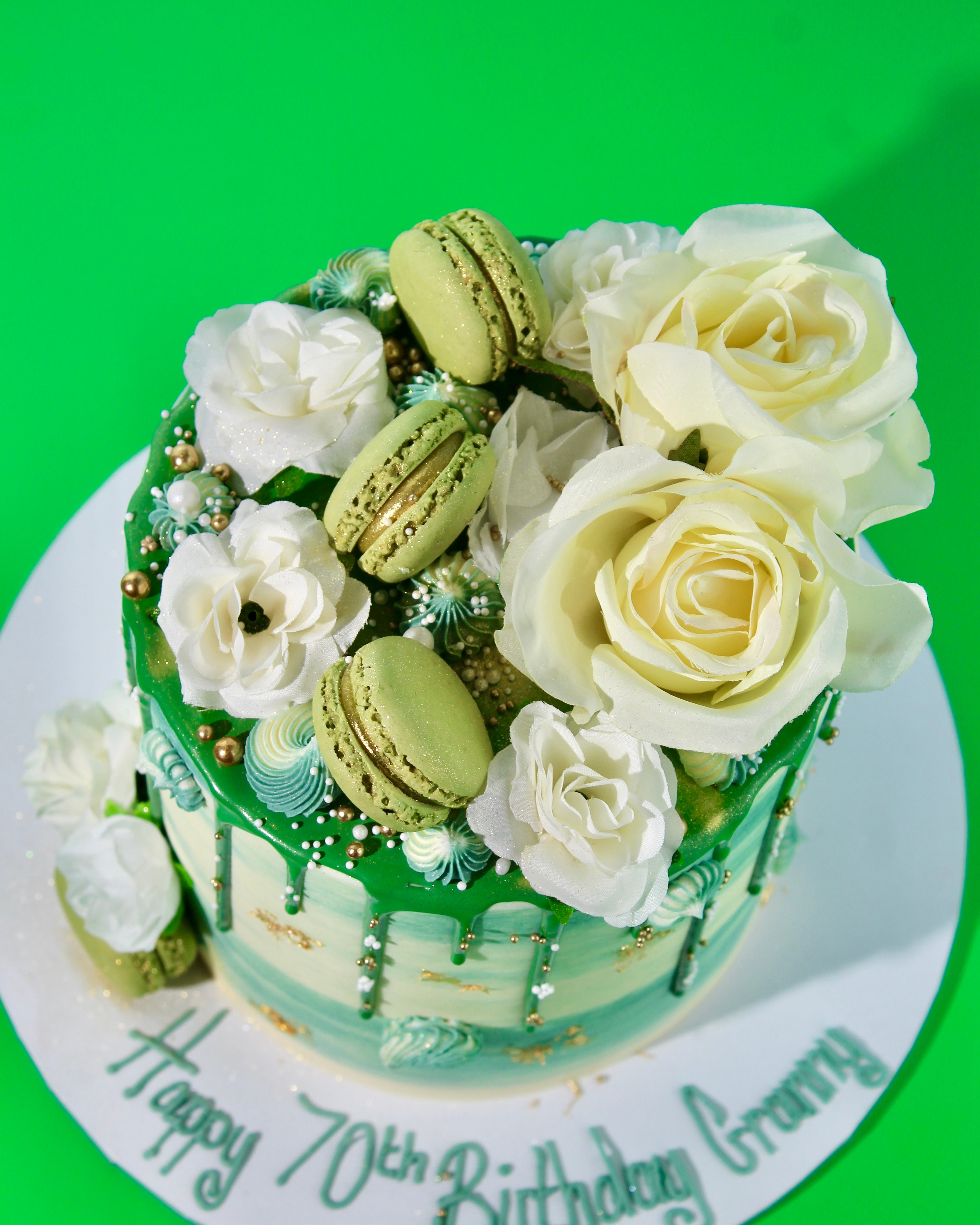 Green chocolate drip with gold leaf flakes and pearl sprinkles on white buttercream cake