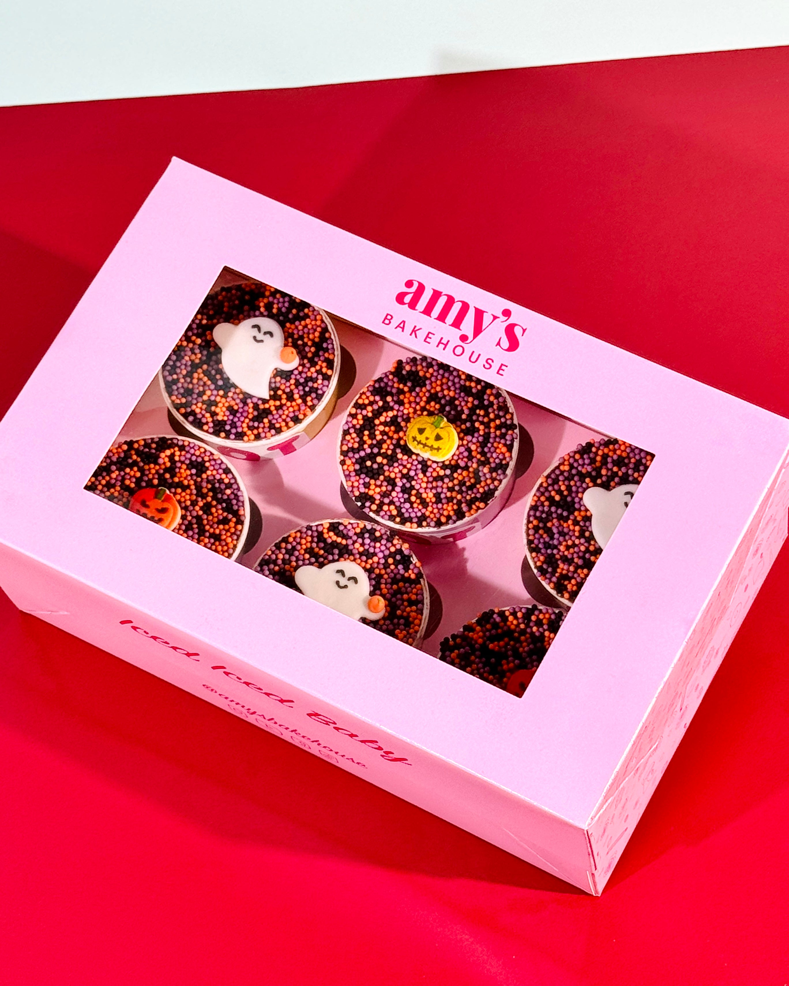 Box of six Halloween Dot Cakes in Amy's Bakehouse packaging covered in black orange and purple dot sprinkles with ghost and pumpkin decorations