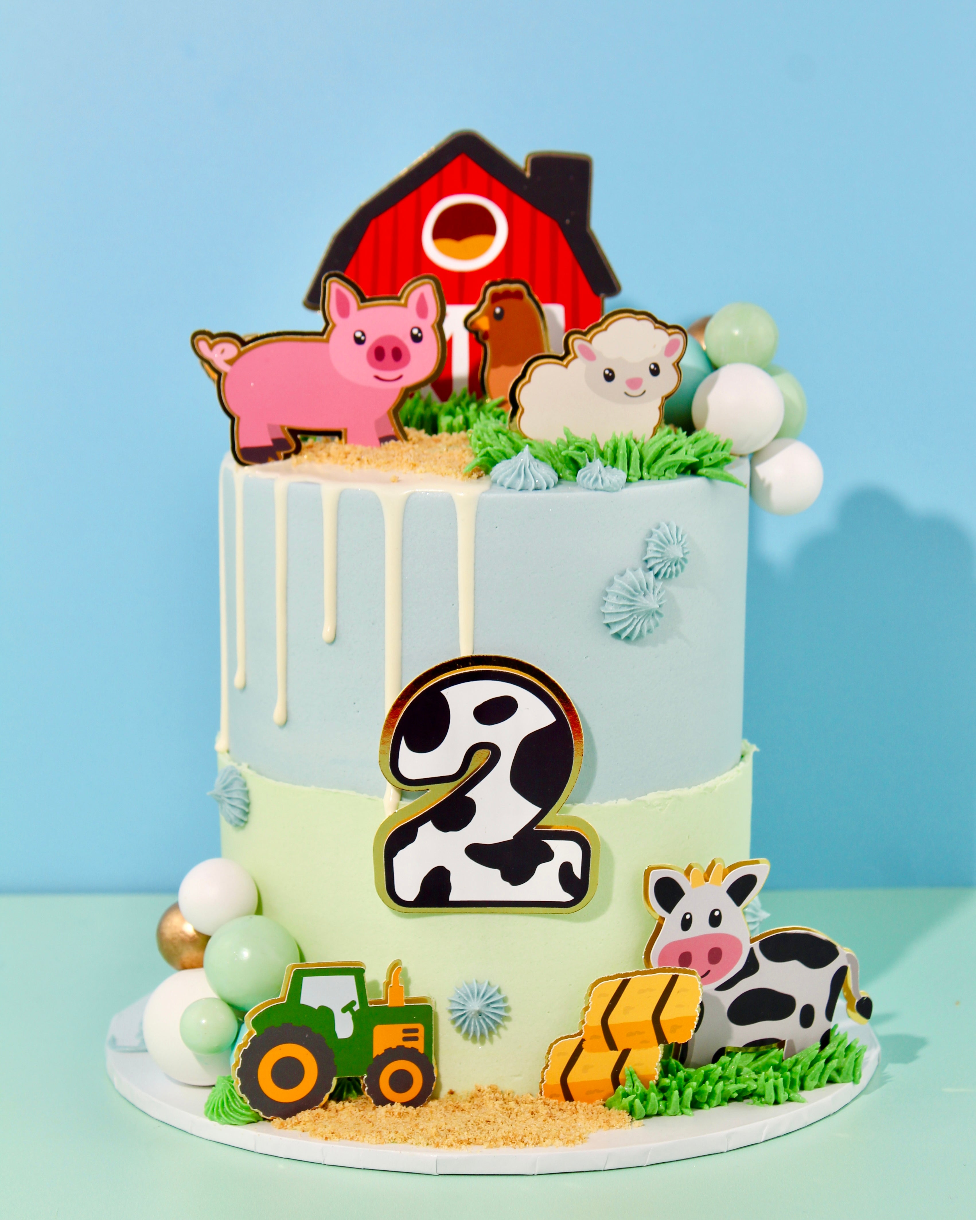 Farm-themed birthday cake with pastel buttercream, barn and animal toppers, tractor decoration and edible grass