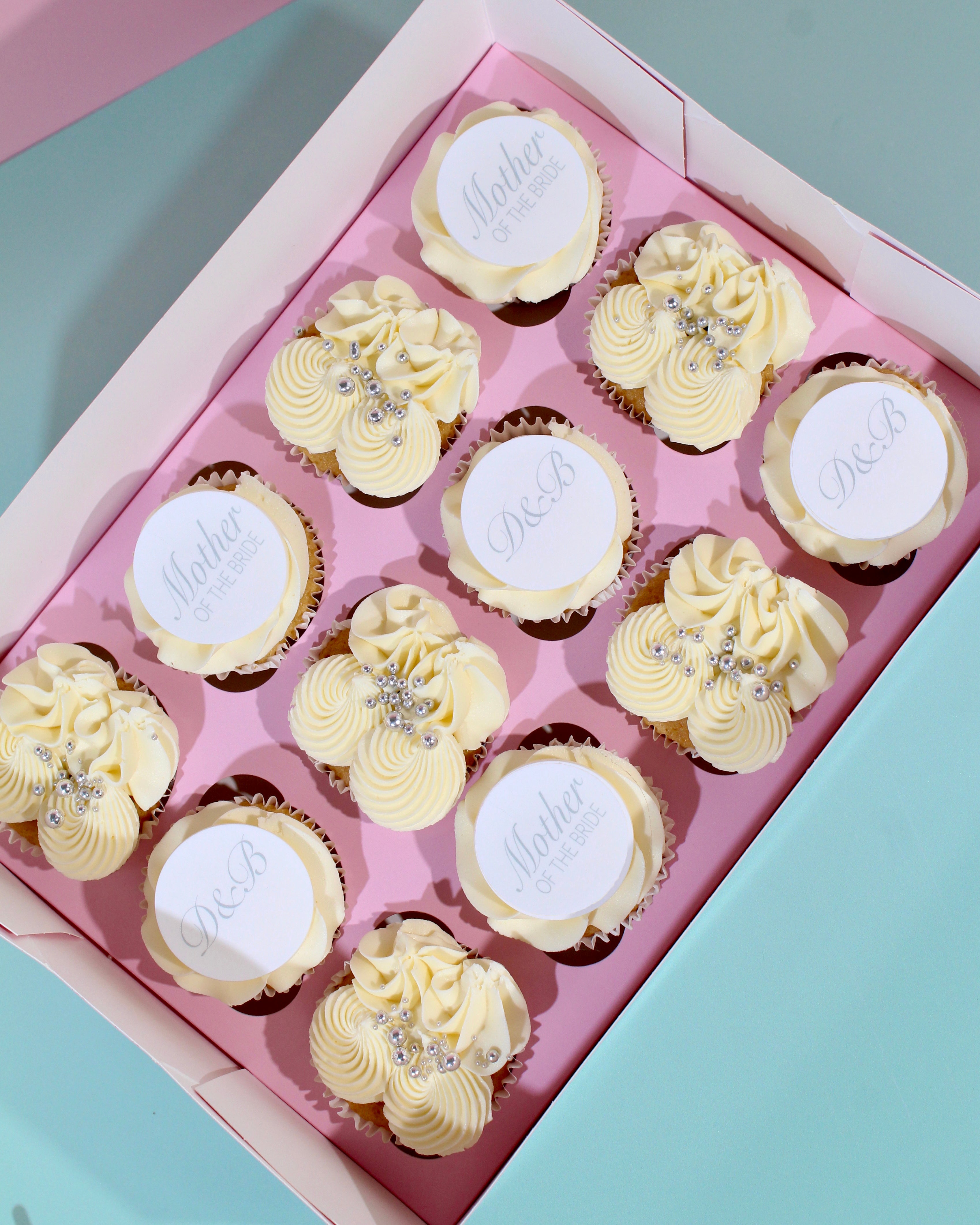 Box of mother of the bride cupcakes with ivory buttercream piping, silver decorations and personalised toppers