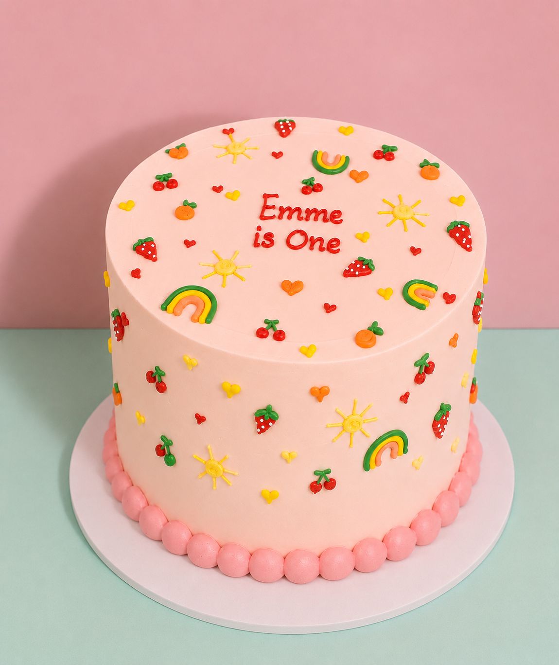 Blush pink birthday cake covered in hand-piped fruit and rainbow doodles with personalised message on top