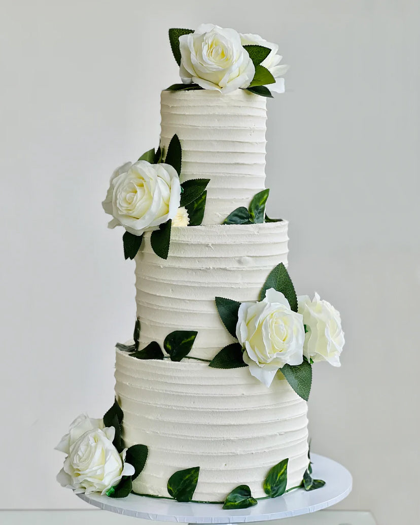 Ivory wedding cake with cascading roses and green vine detailing