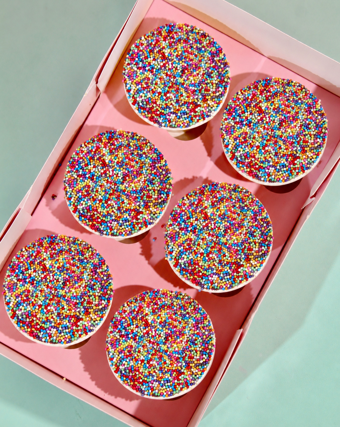 Three Amy's Bakehouse Dot Cake pots in yellow, pink and orange covered in rainbow sprinkles