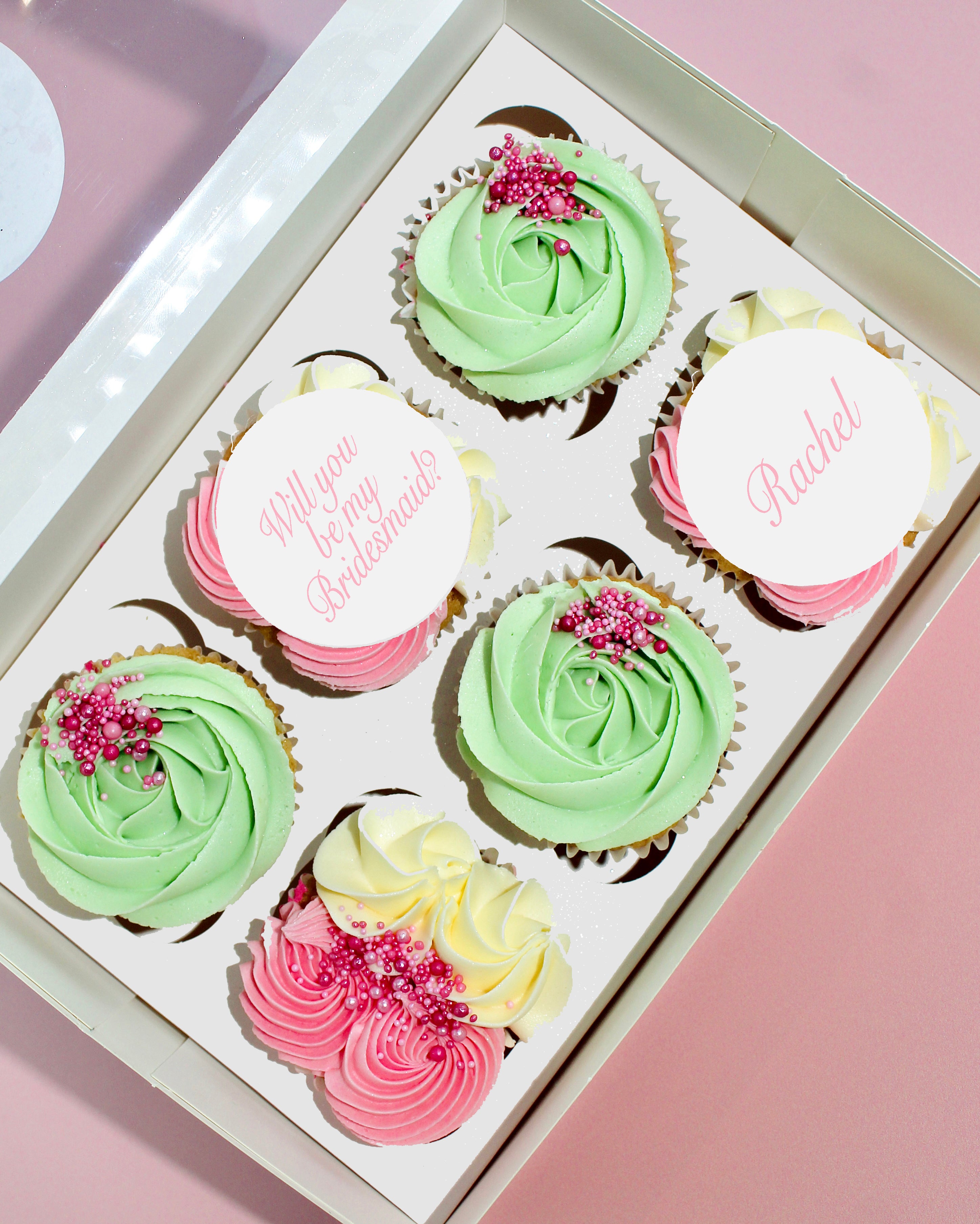Pastel pink and mint bridesmaid proposal cupcakes with personalised edible toppers in a gift box.
