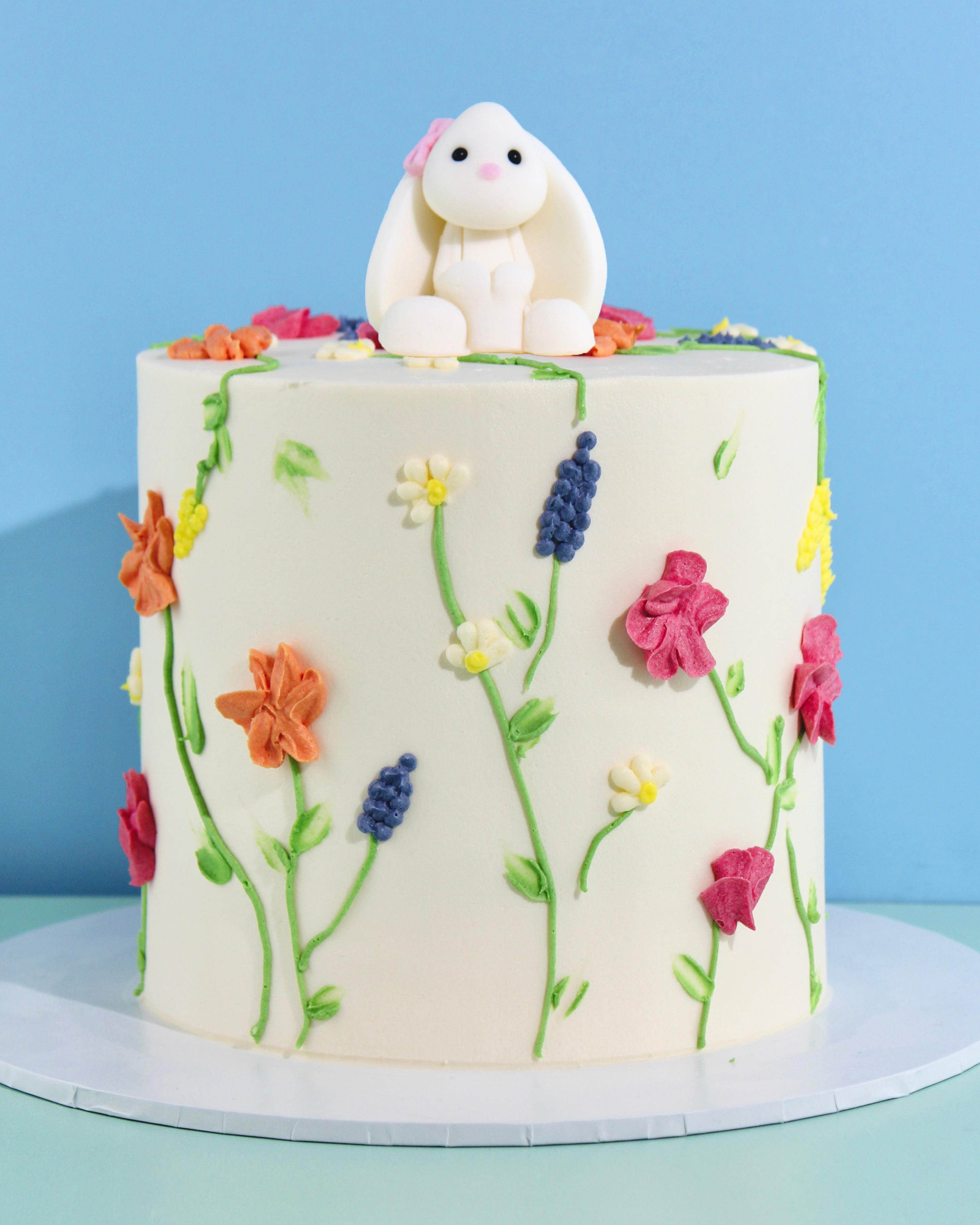 Buttercream cake decorated with colourful piped wildflowers and topped with a cute white fondant bunny